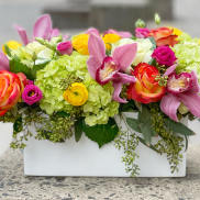 Colorful floral arrangement in a white rectangular vase