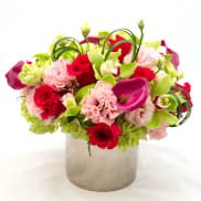 Bouquet of red roses, pink carnations, and green calla lilies in a silver vase