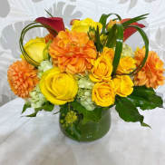 Yellow roses and orange dahlias in a green vase