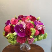 Bright mixed bouquet in a clear glass vase with purple orchids and pink roses