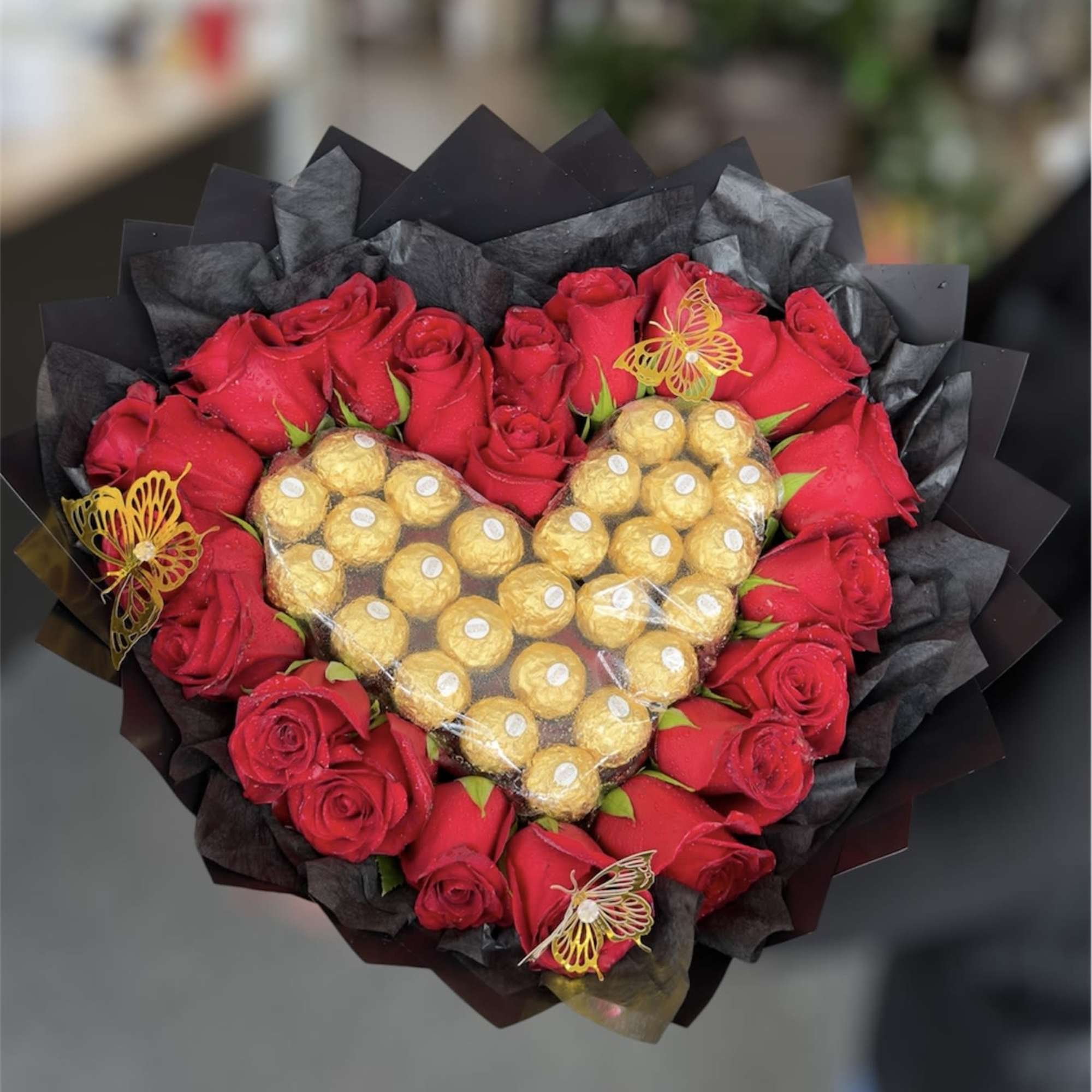 Beautiful bouquet with a heart made of chocolates and roses around it
Roses