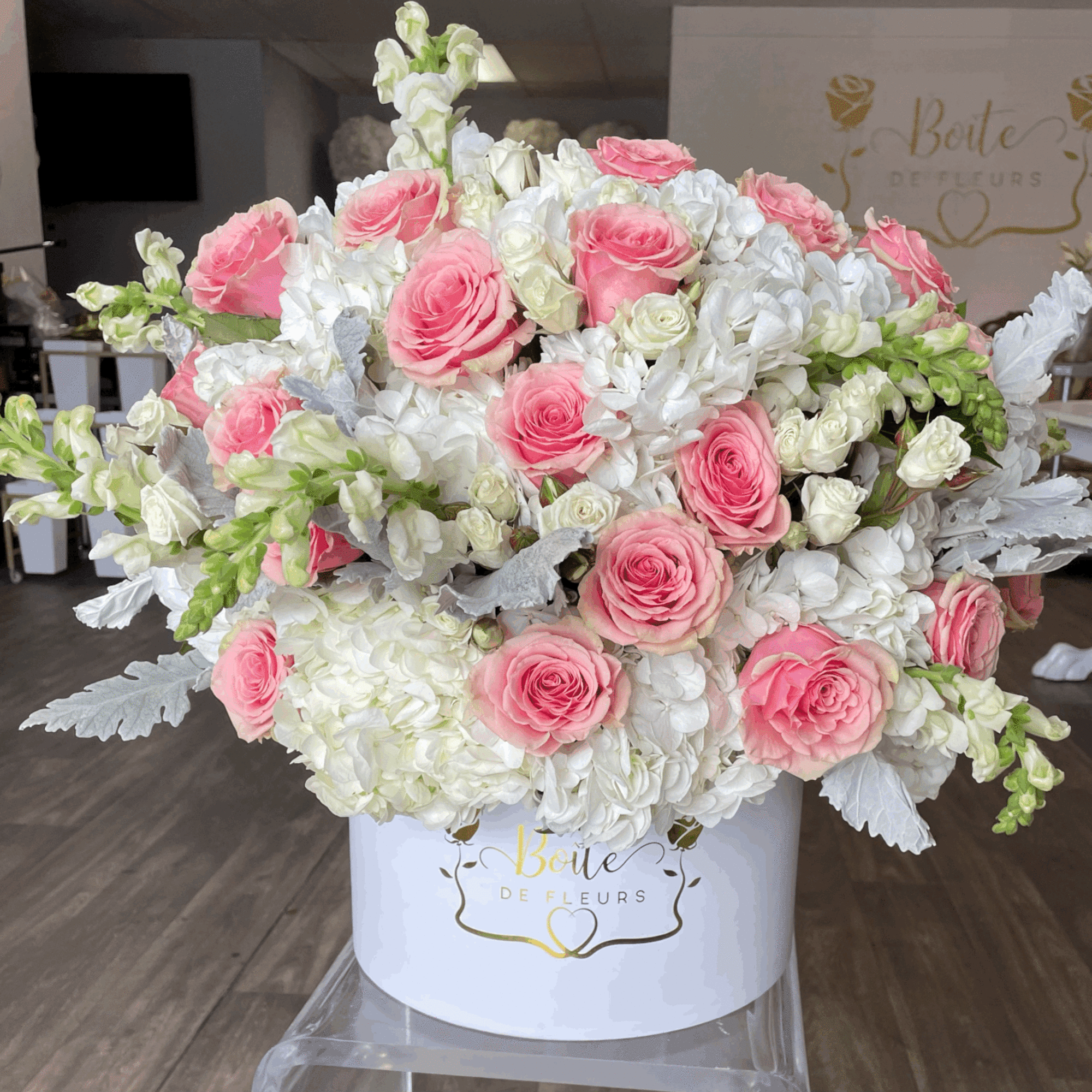 Pink roses and white flowers arranged in a white hat box