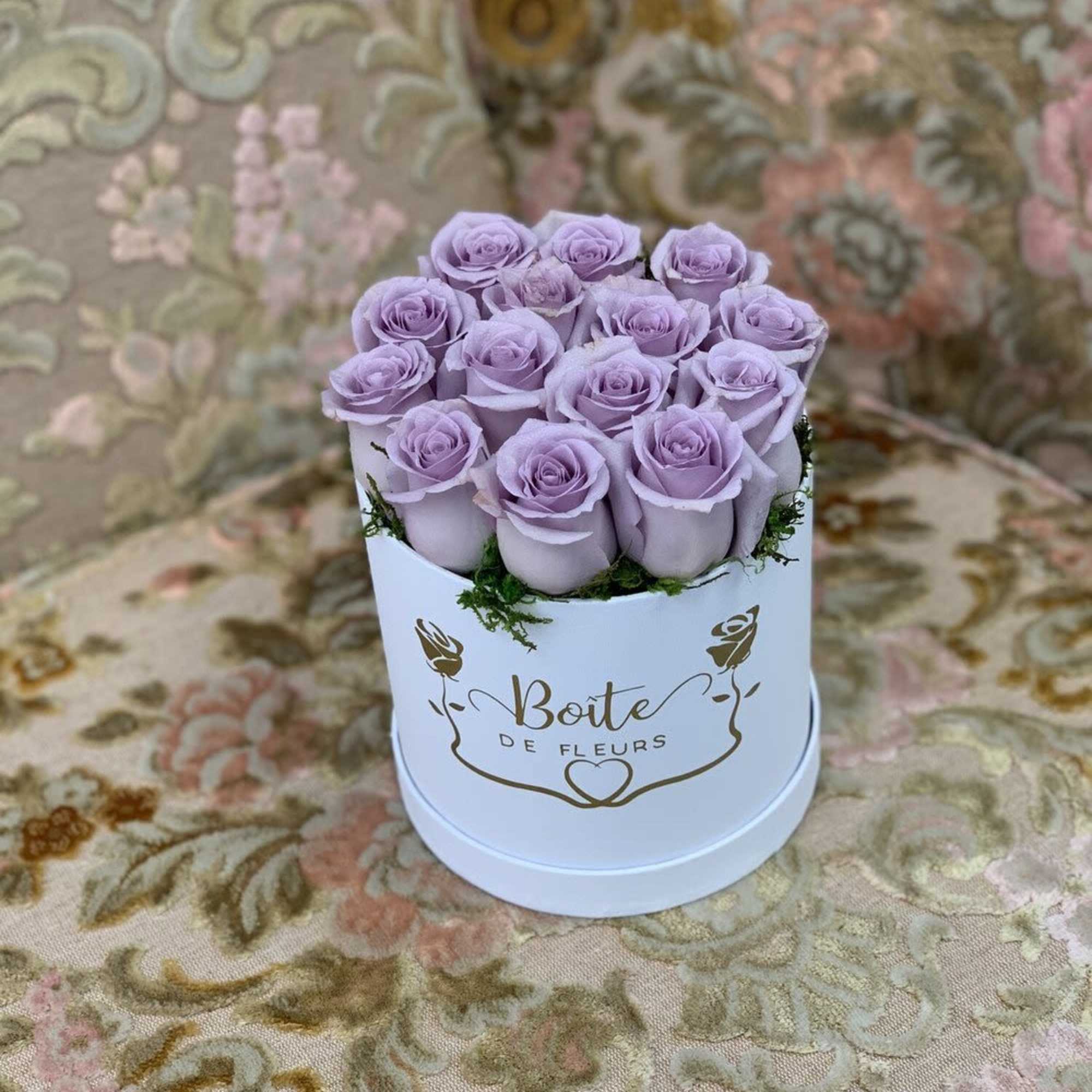 Lavender roses arranged in a white round box