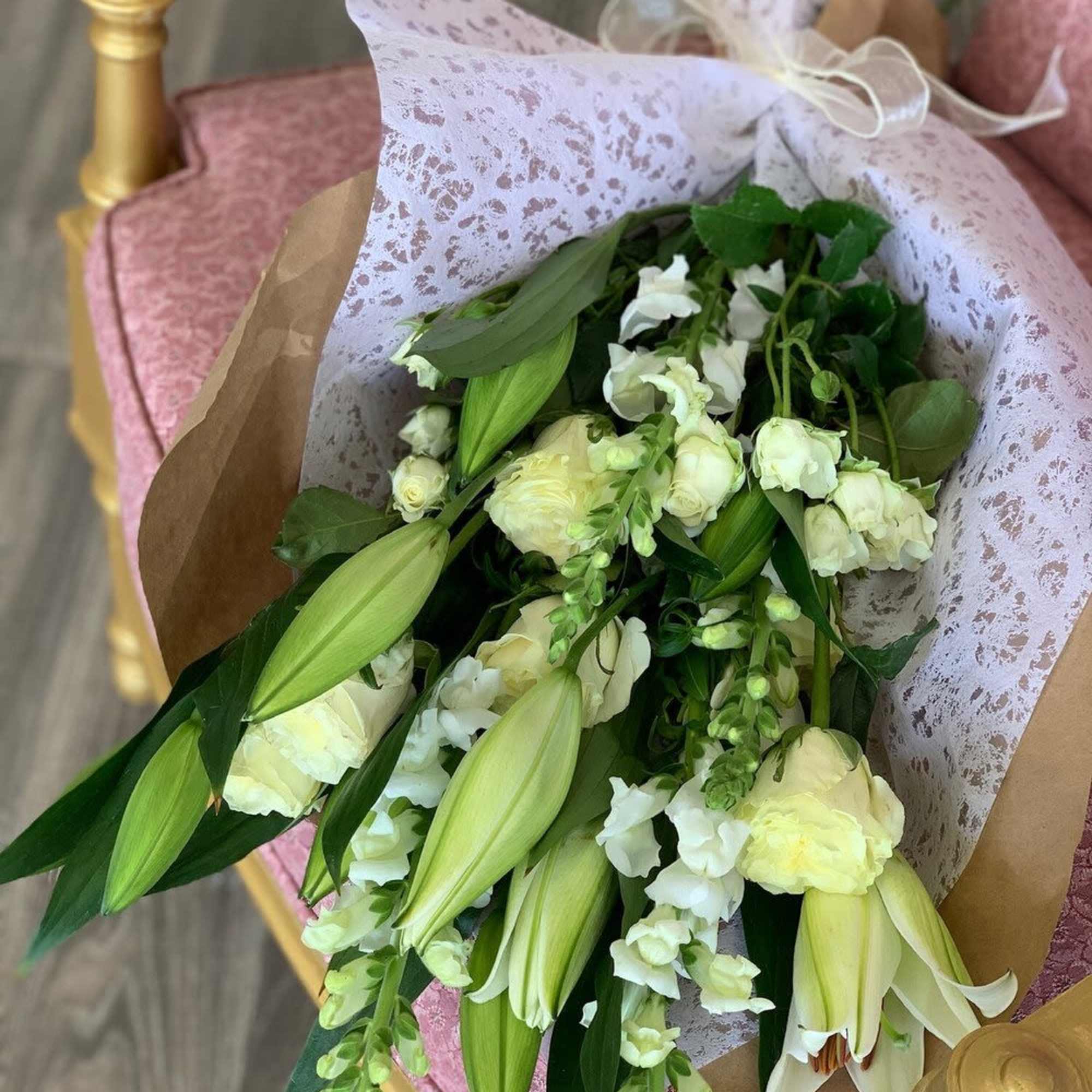 Bouquet of white lilies and roses wrapped in patterned paper