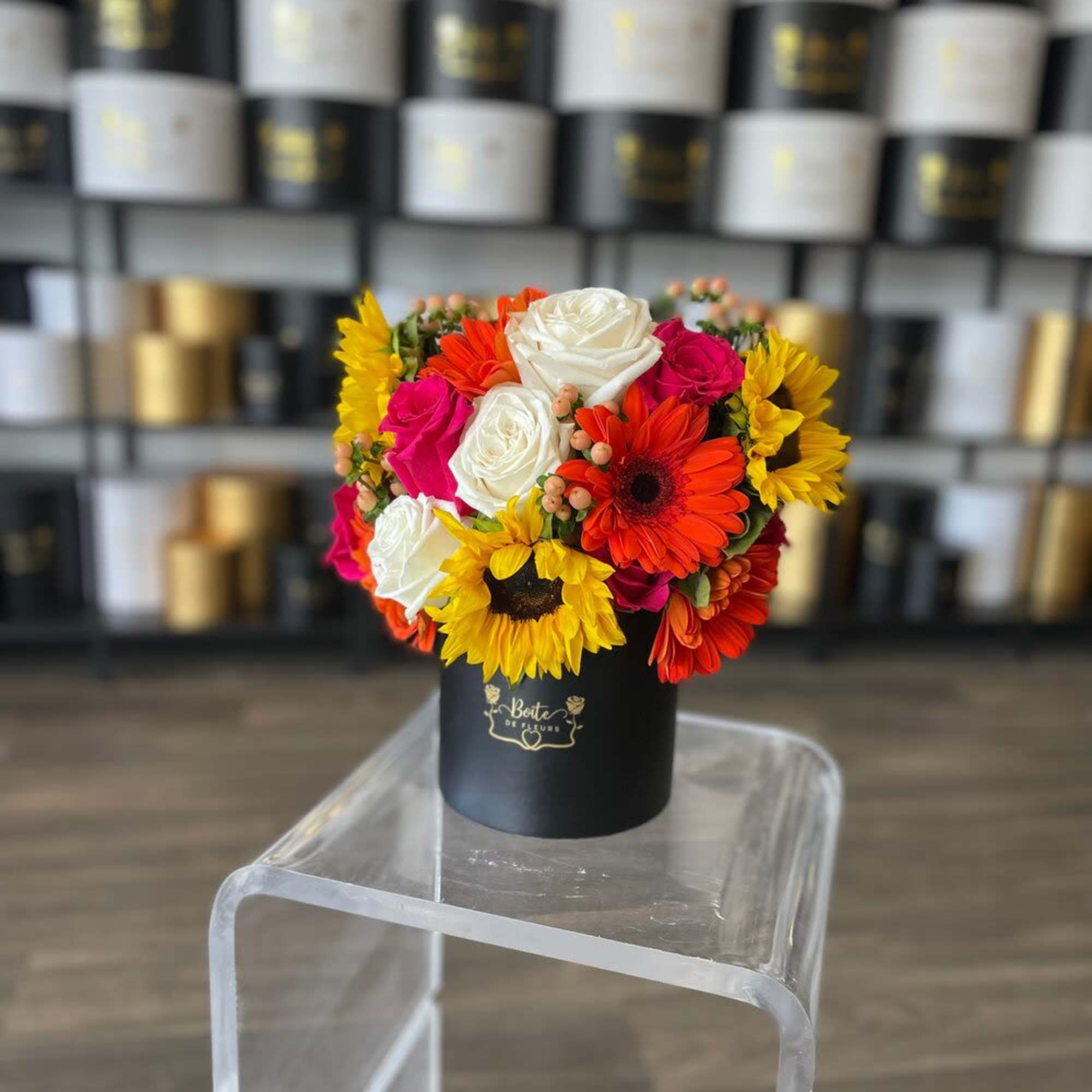 Colorful bouquet of roses and sunflowers in a black hat box