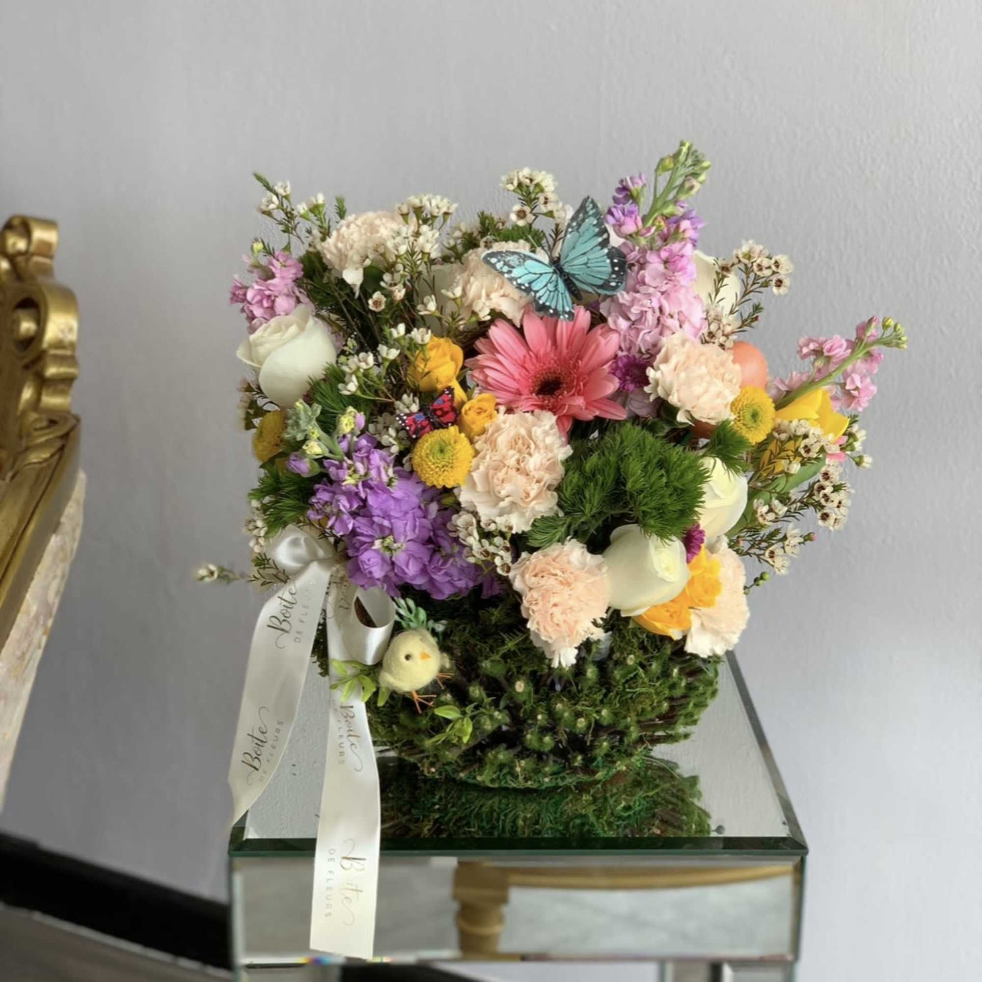 Mixed bouquet with pink, white, and yellow flowers in a mirrored container