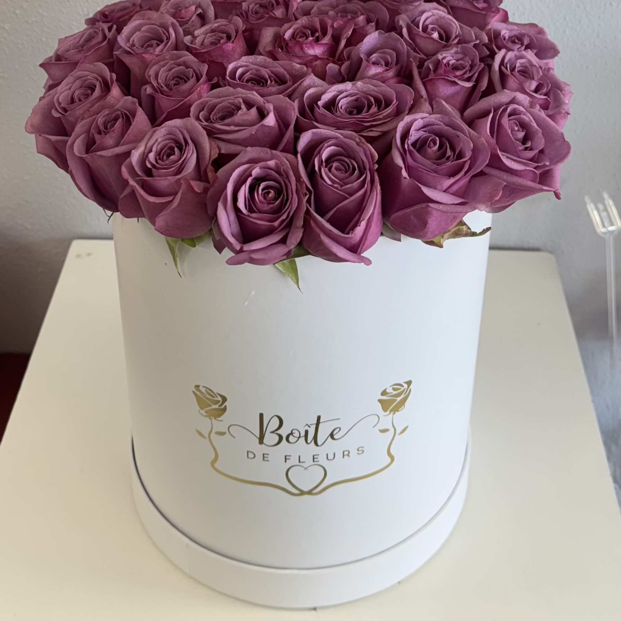 Round box of purple roses on a white table
