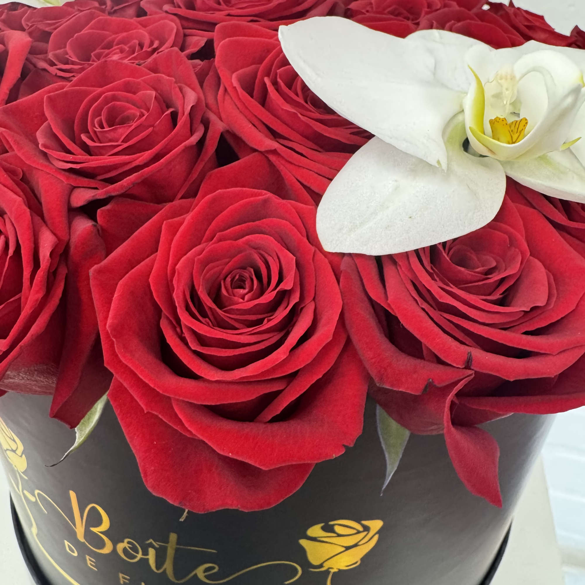 Red roses with white orchids in a black round box