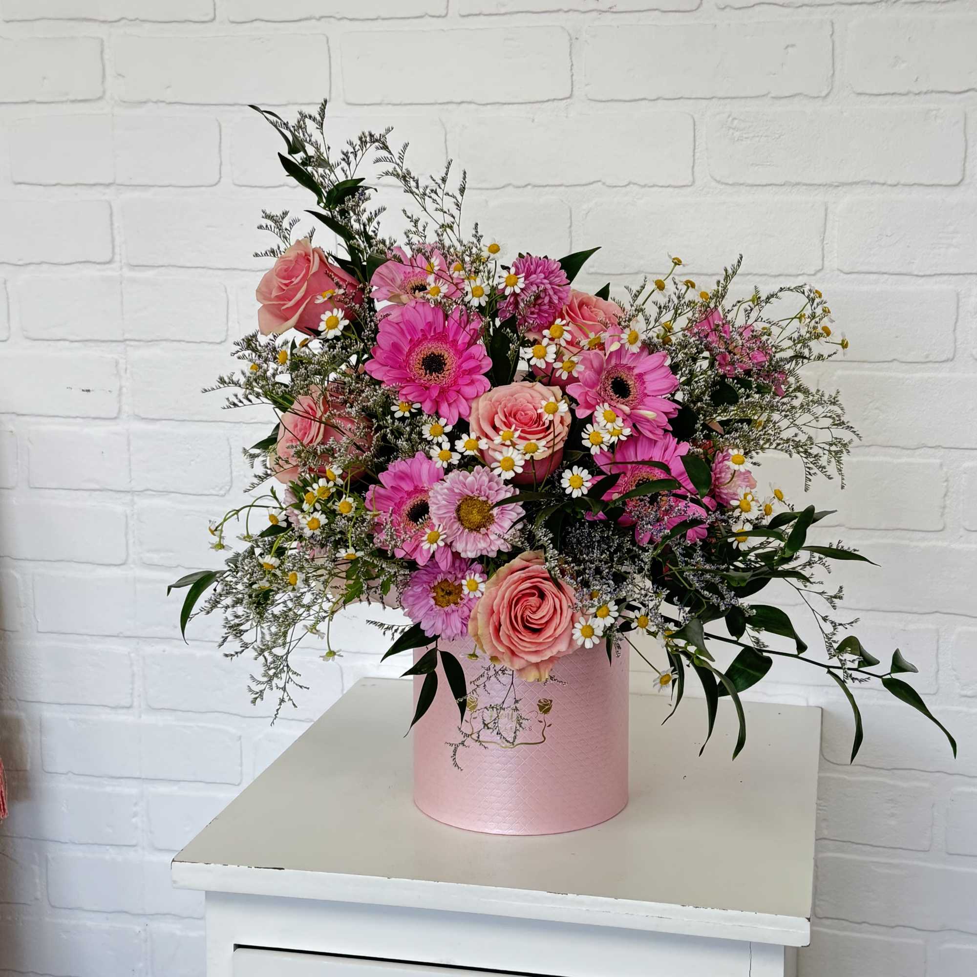 Pink mixed flower arrangement in a round pink box