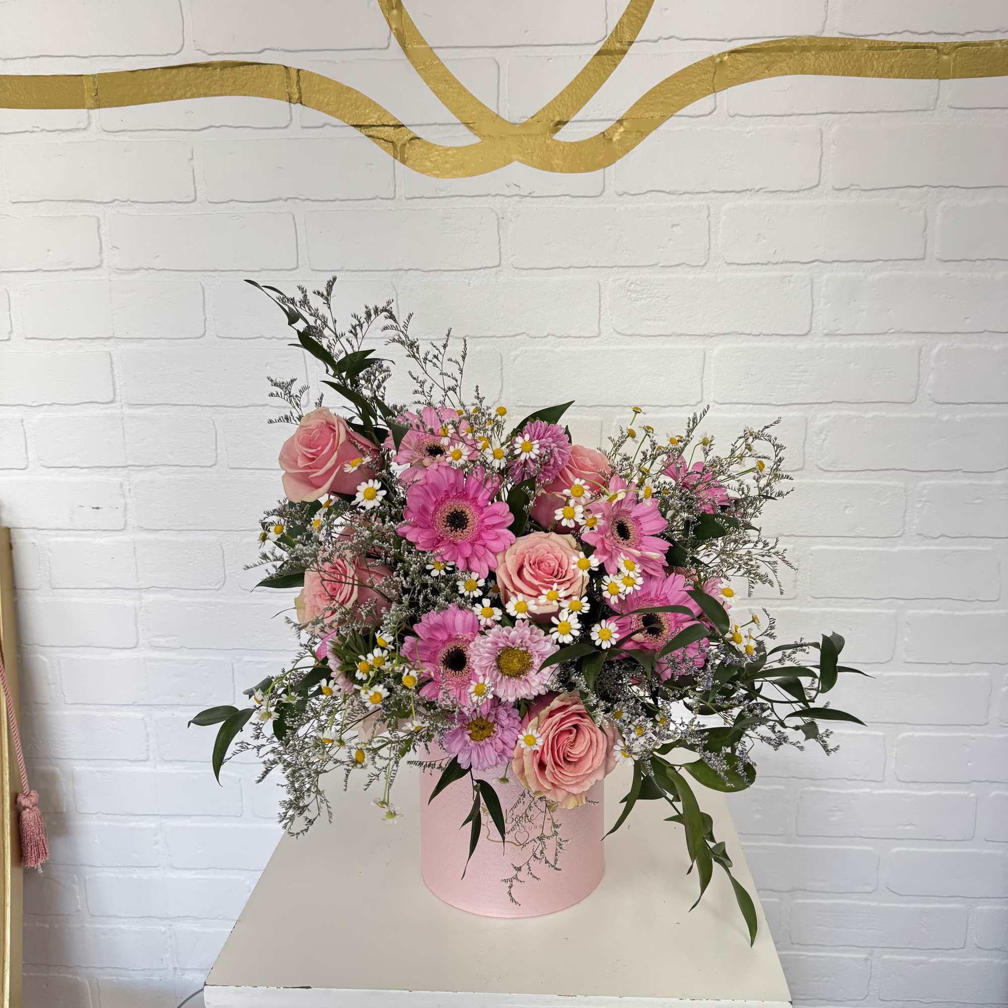 Pink roses and gerbera daisies in a pink hatbox