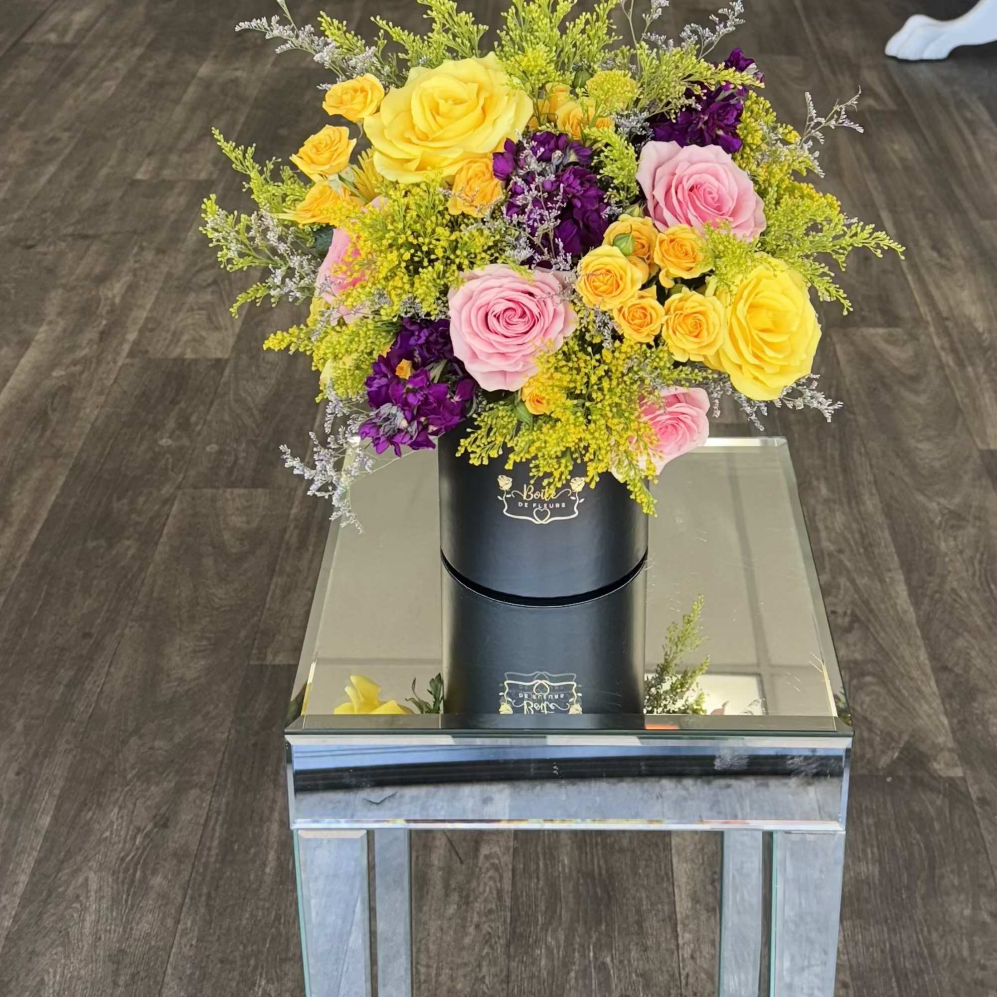 Colorful bouquet of yellow, pink, and purple roses in a black box