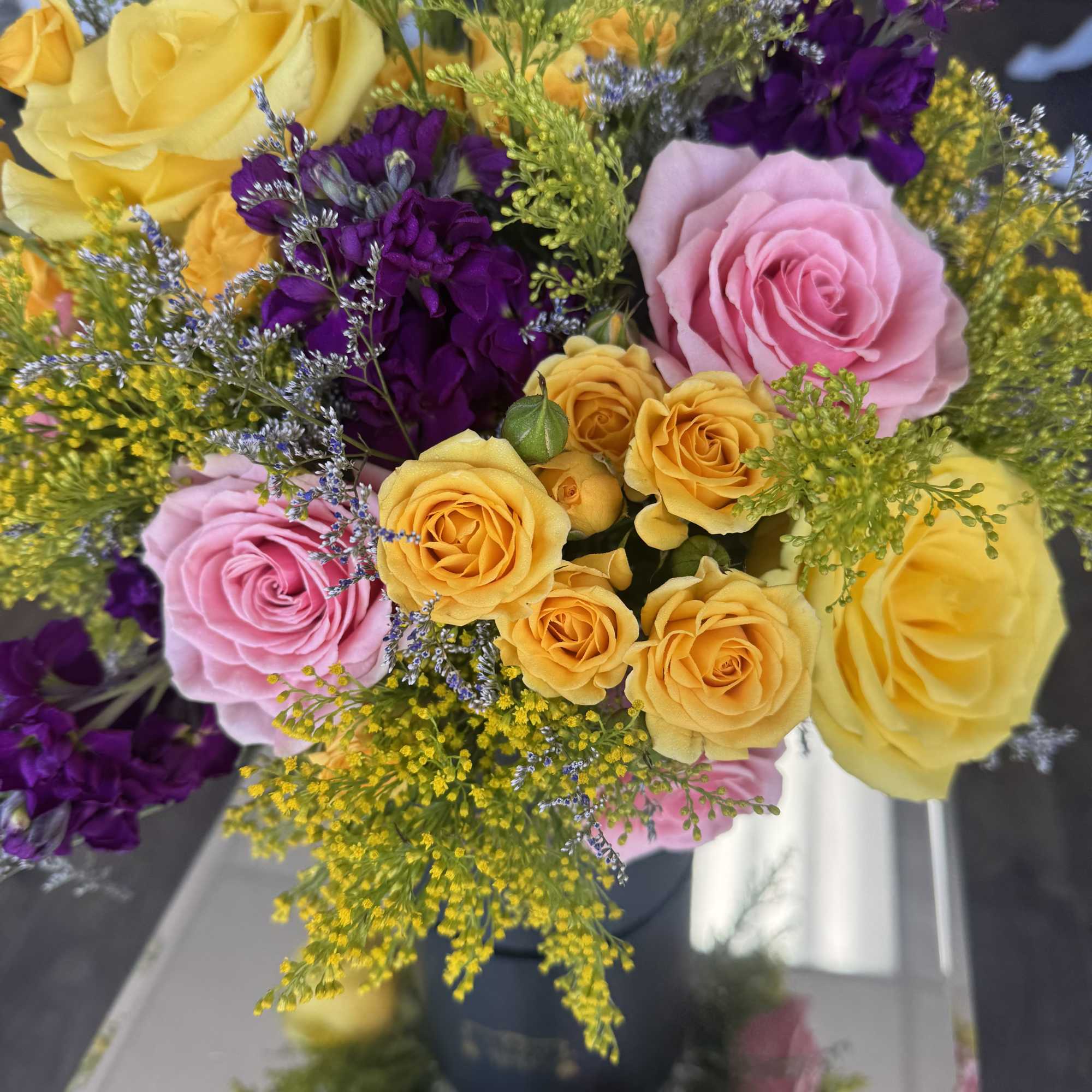 Bouquet of pink, yellow, and purple roses with airy filler flowers