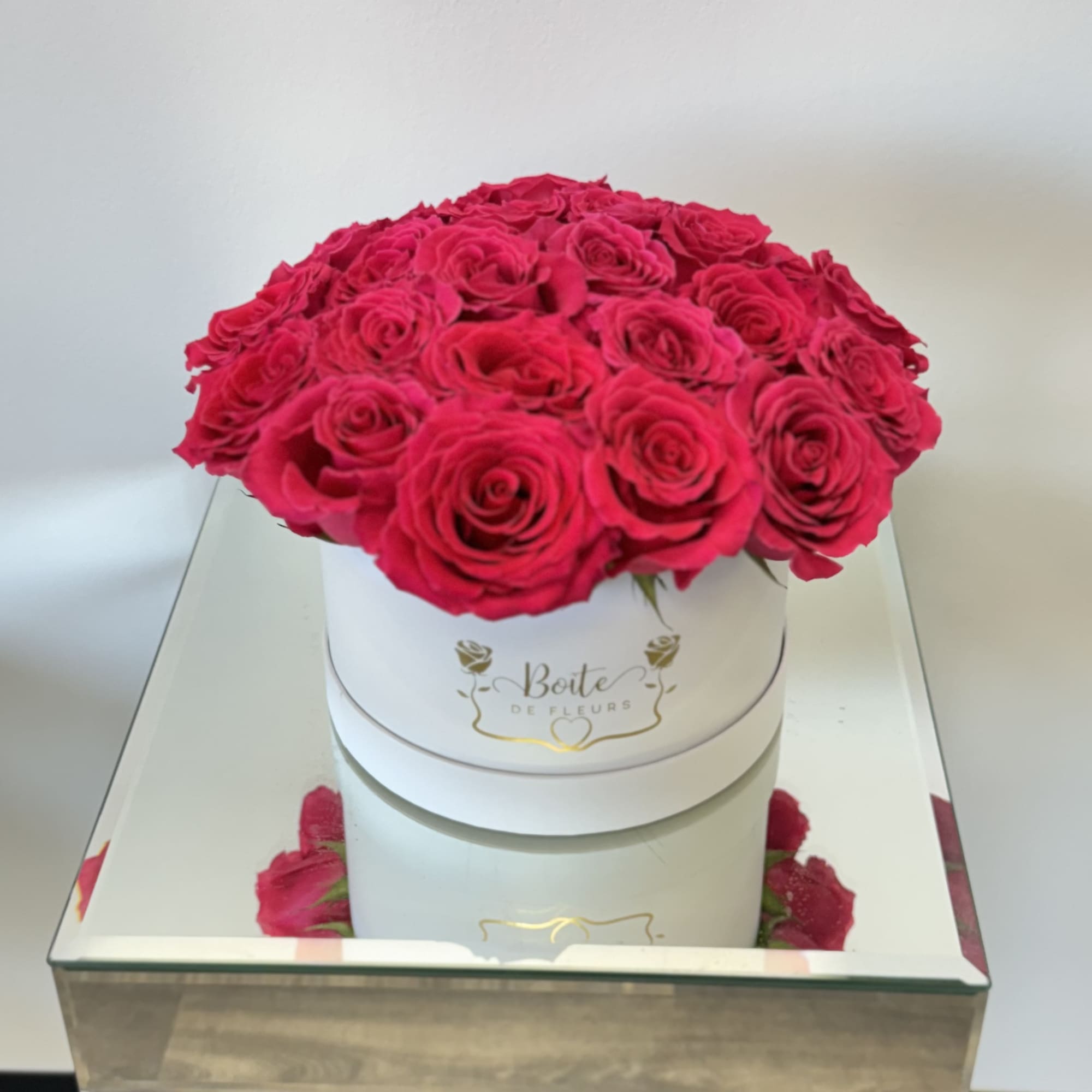 Round box of hot pink roses on a mirrored table