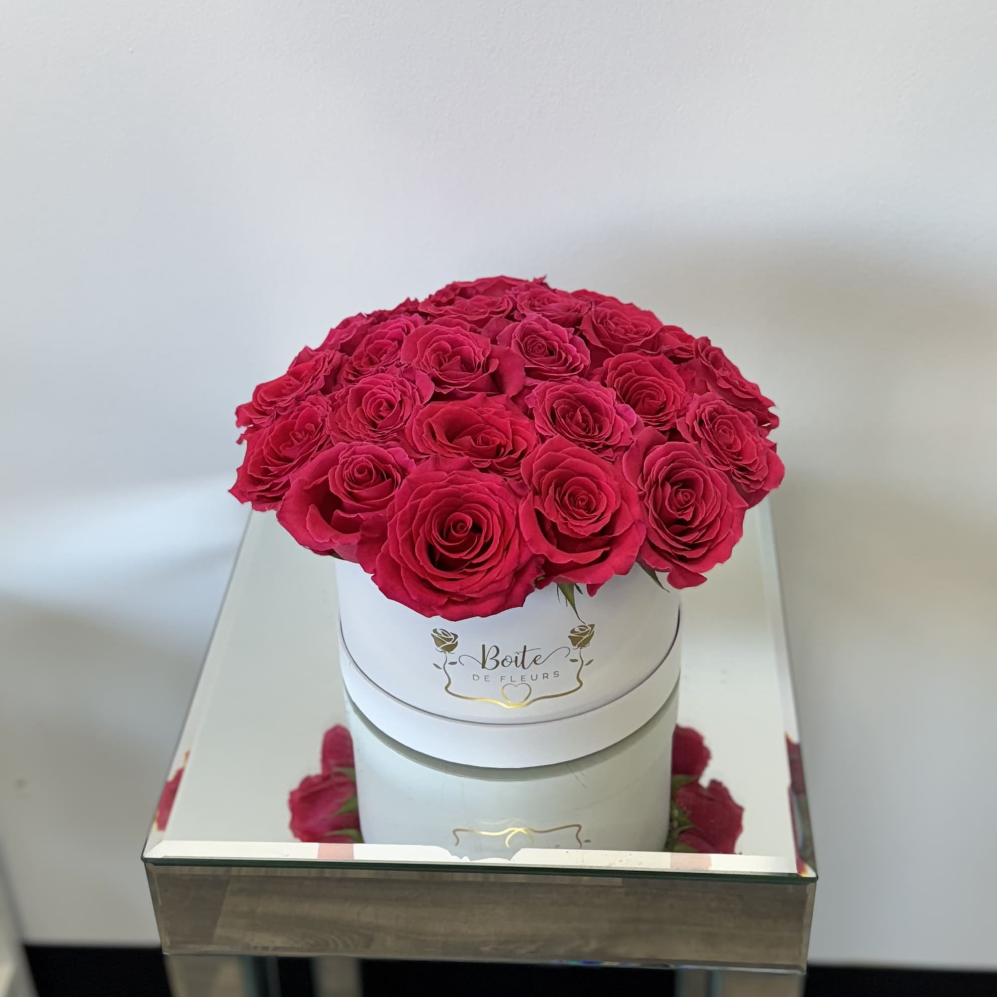Round box of red roses on a mirrored table
