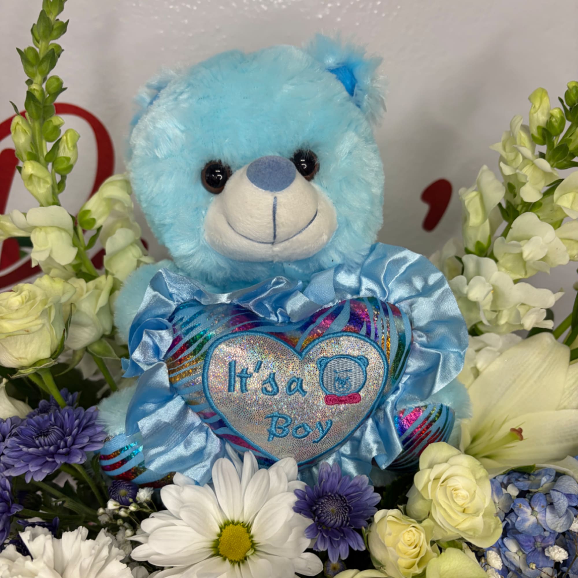 Blue teddy bear surrounded by white and purple flowers with an "It's a Boy" heart
