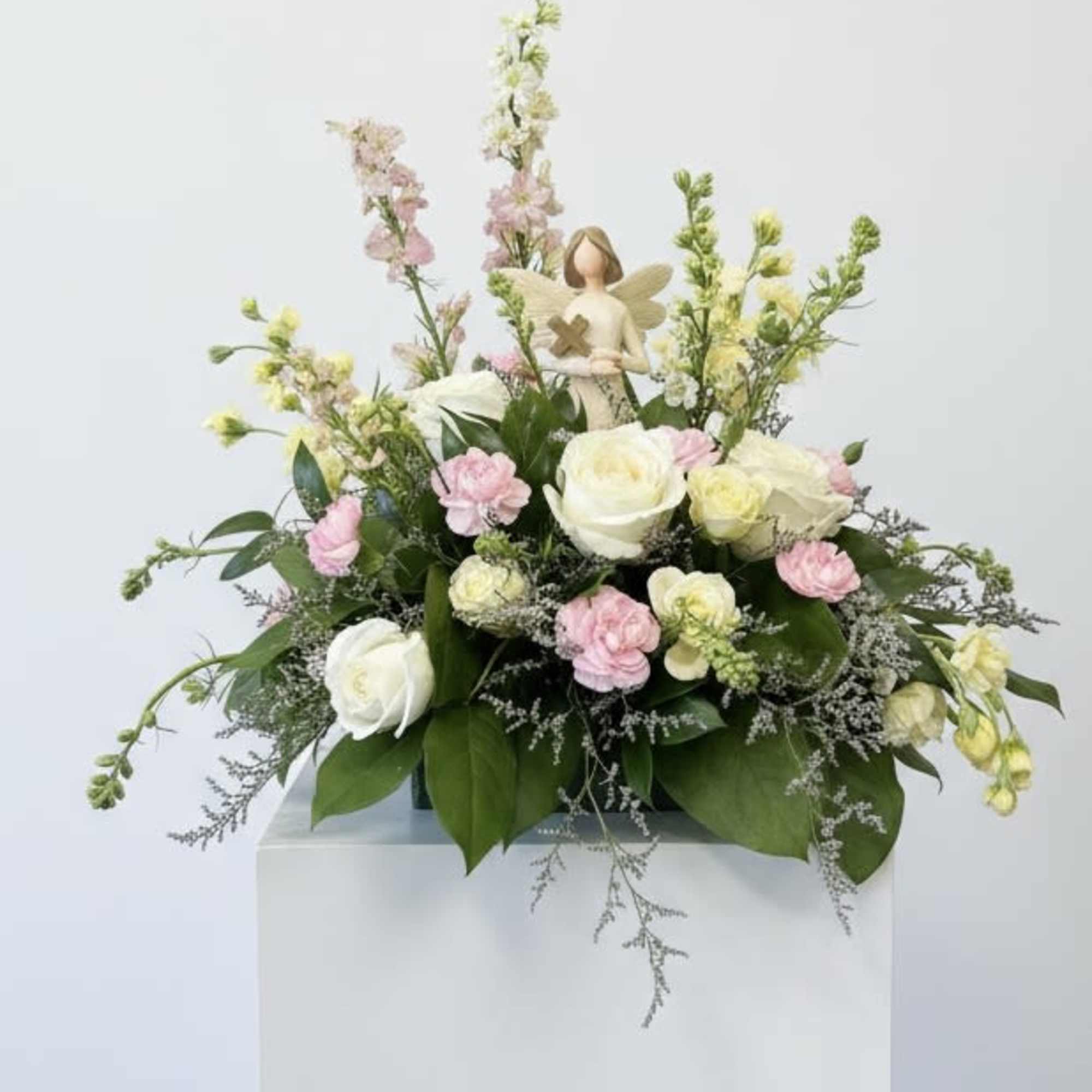 Pastel floral arrangement with roses and carnations on a pedestal