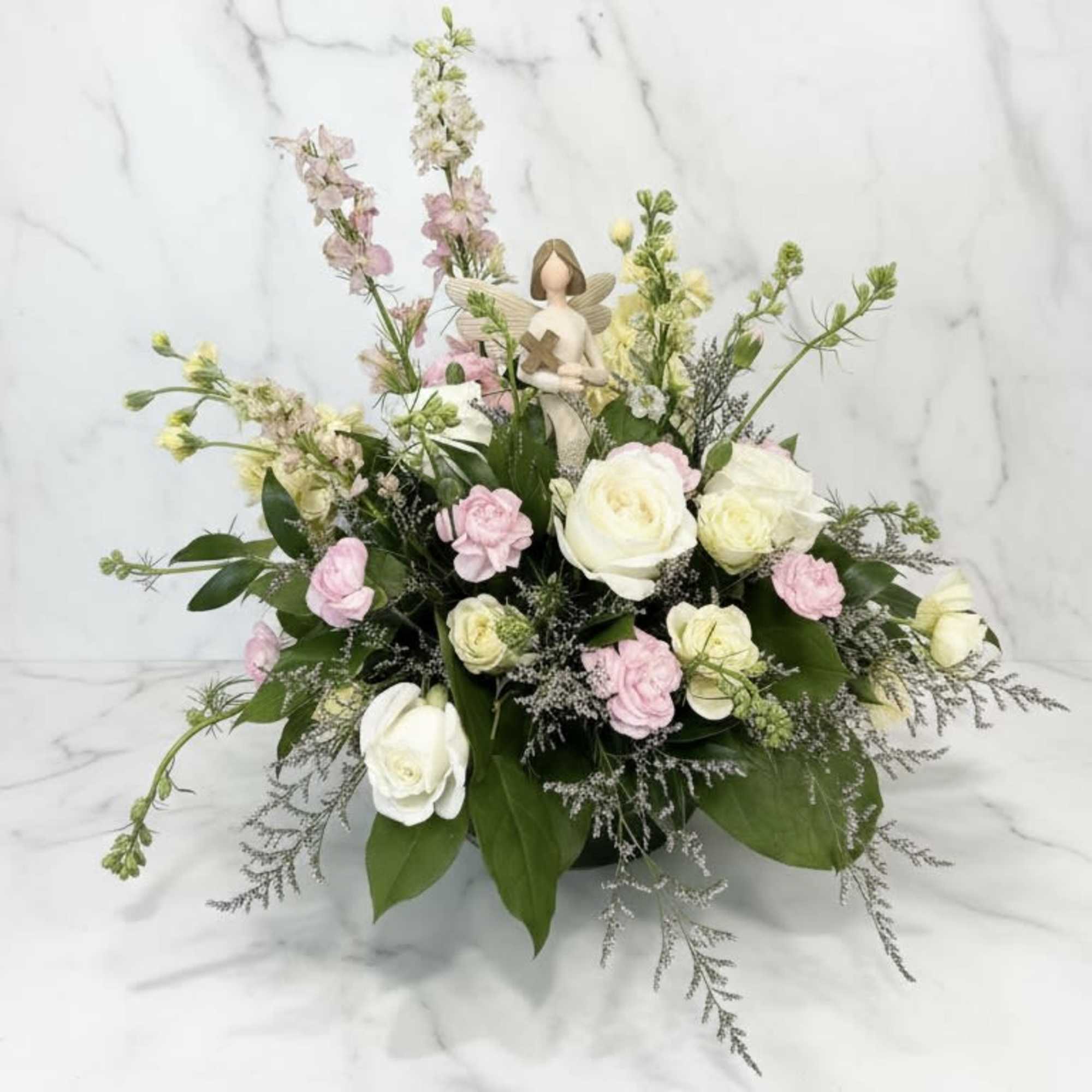 Pink and white floral arrangement with a small angel figurine