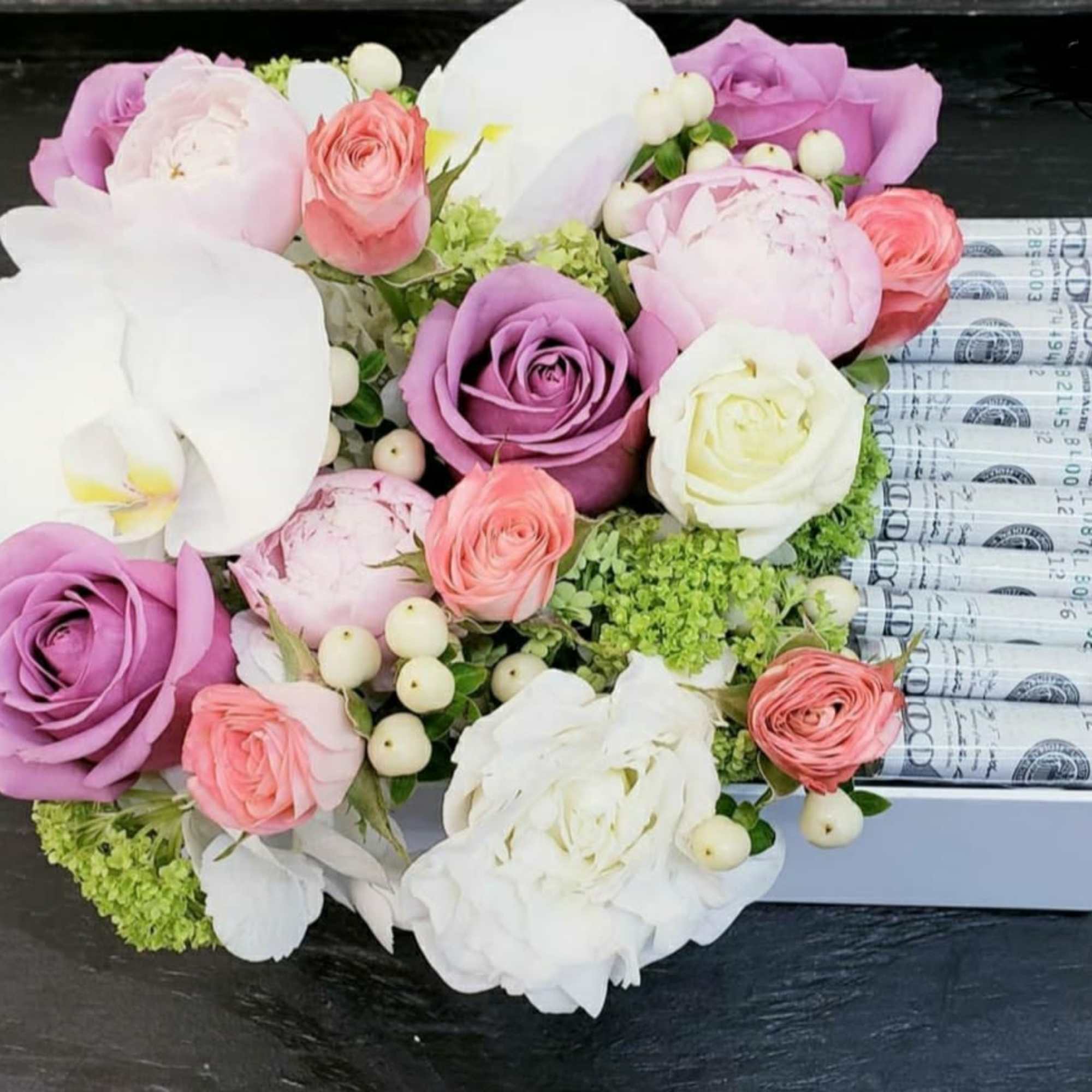 Bouquet of pink, purple, and white flowers with rolled dollar bills