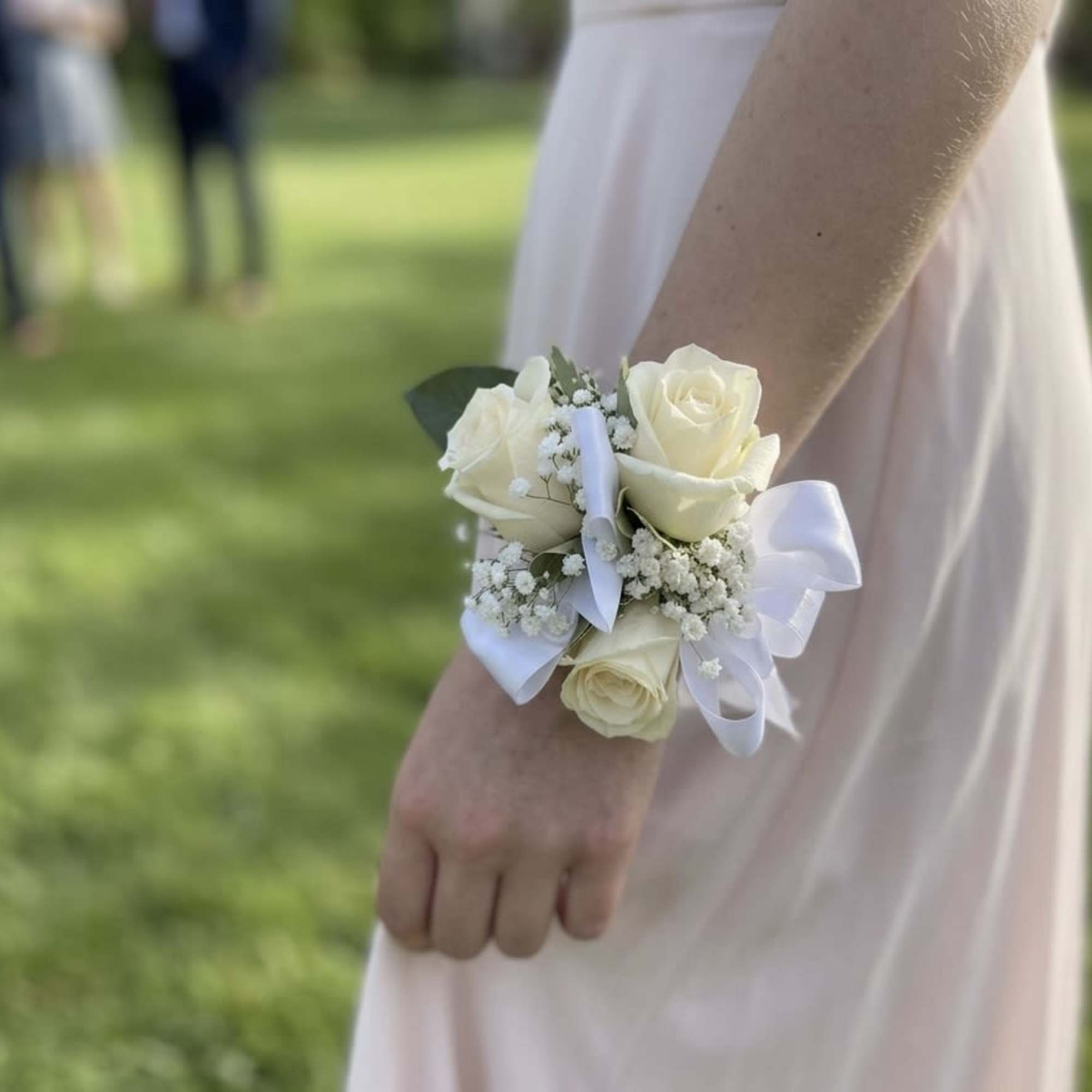 An elegant and classic wrist corsage featuring 3 premium white spray roses