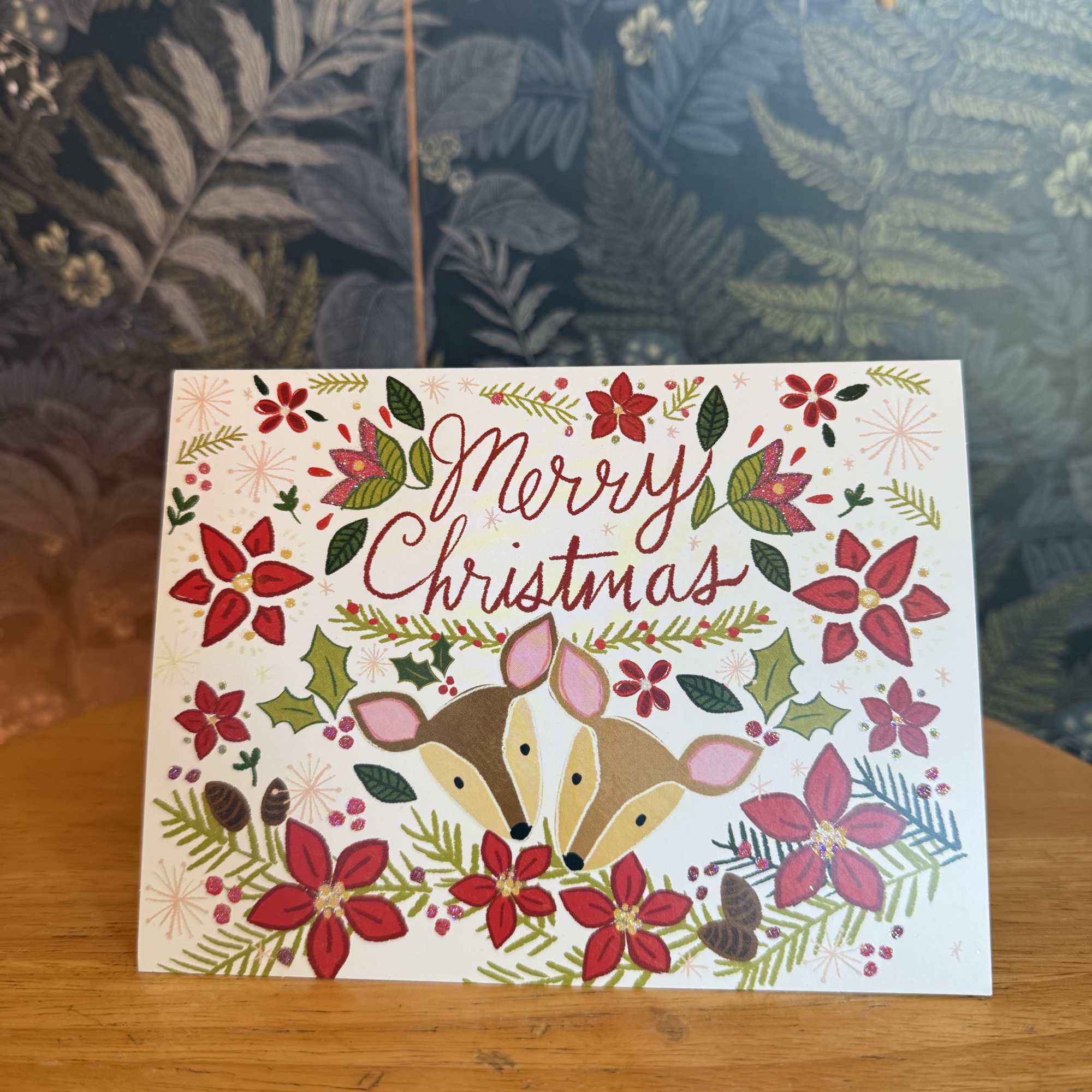 Christmas card with two deer and red floral decorations