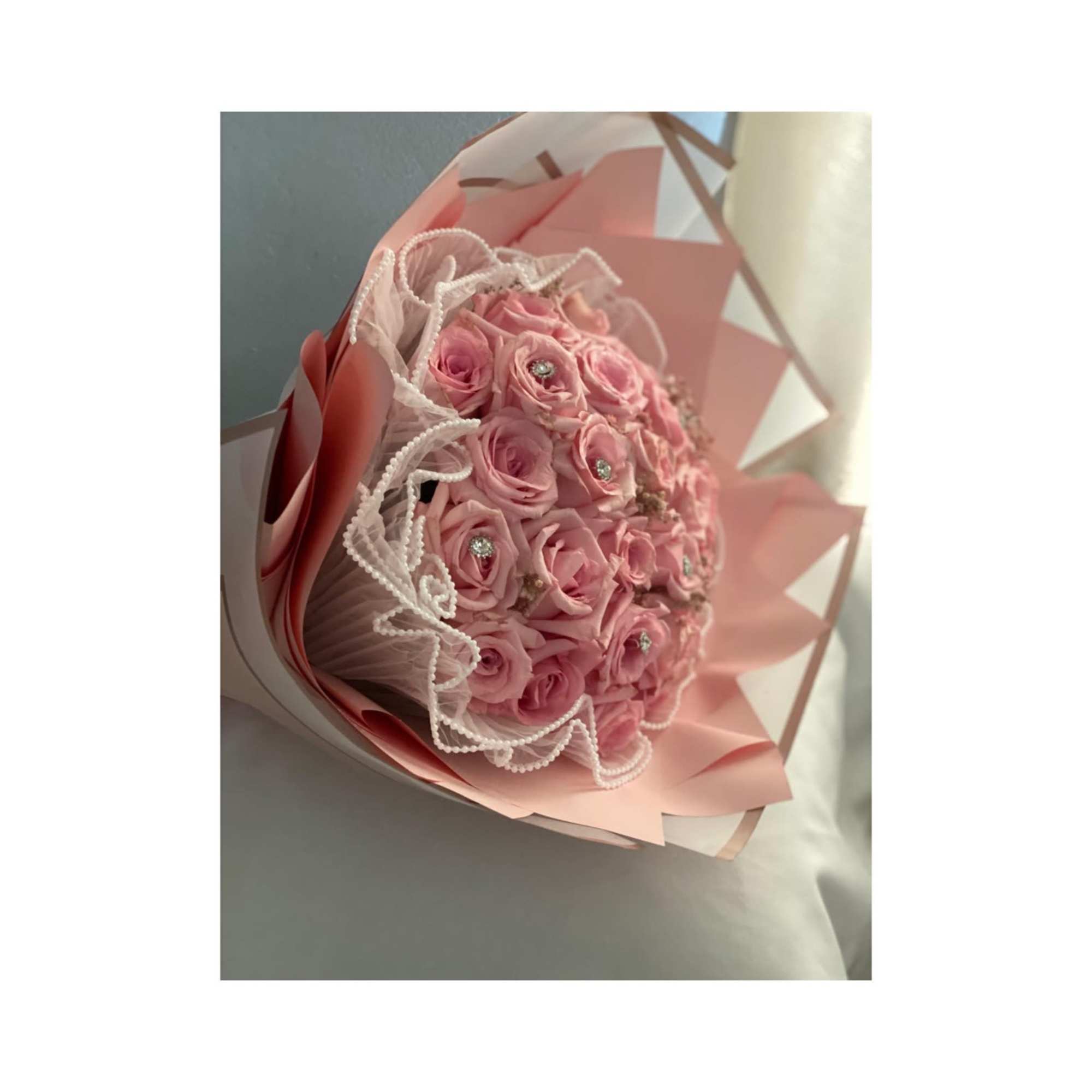 Pink rose bouquet wrapped in pastel paper with lace trim