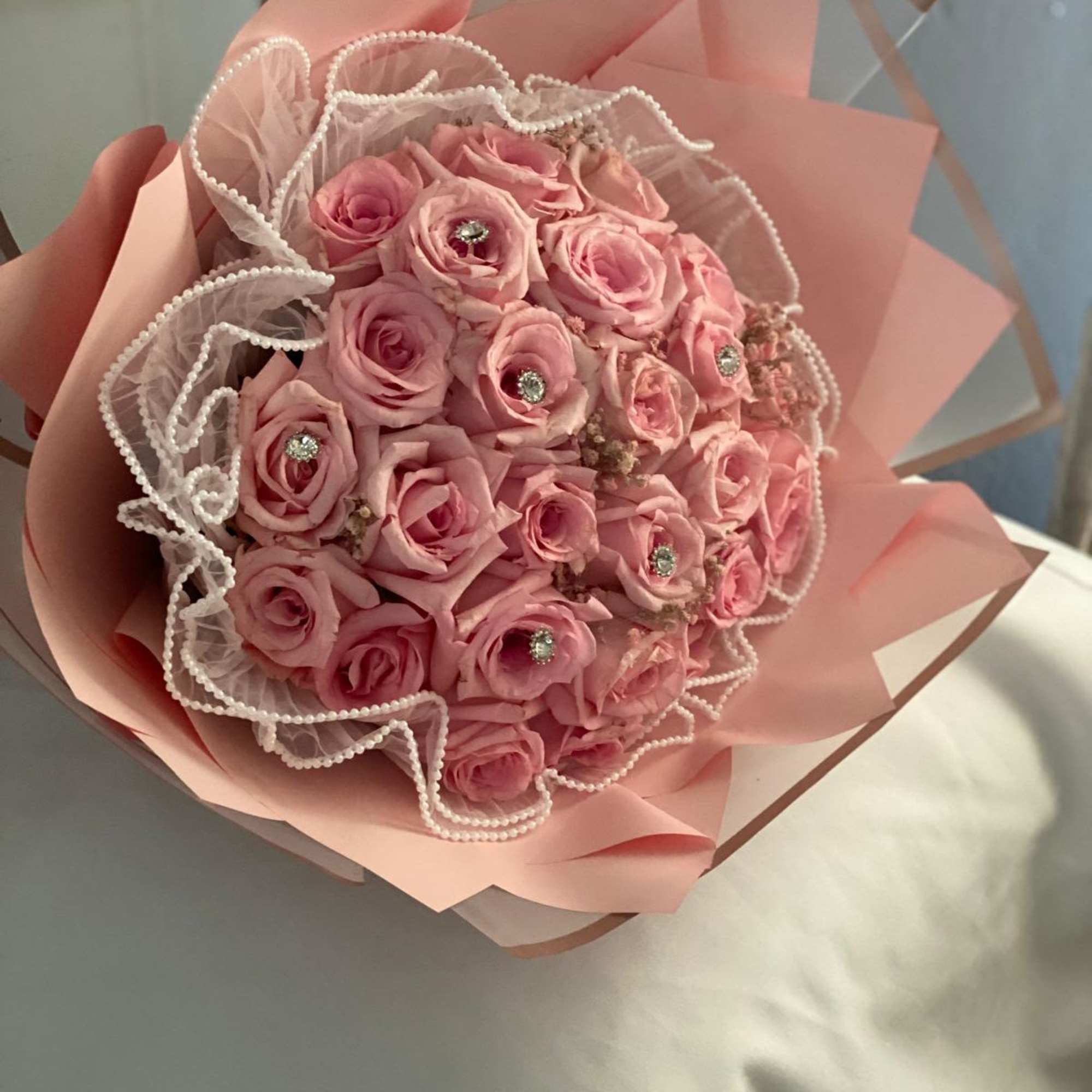 Pink rose bouquet wrapped in pale pink paper with pearl trim