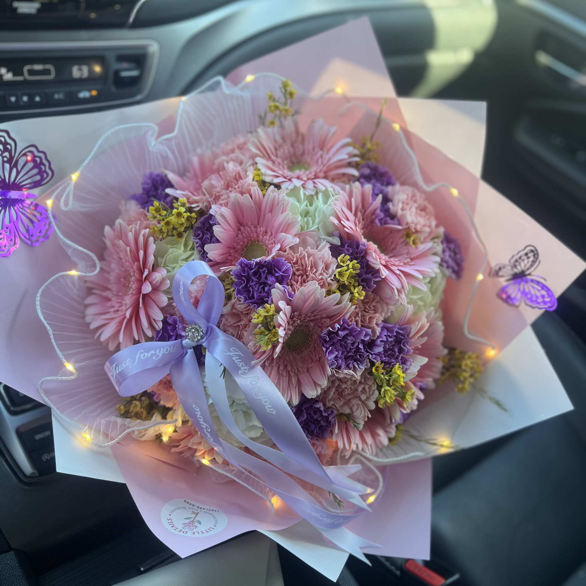 Pink and purple mixed bouquet wrapped in pastel paper with a ribbon