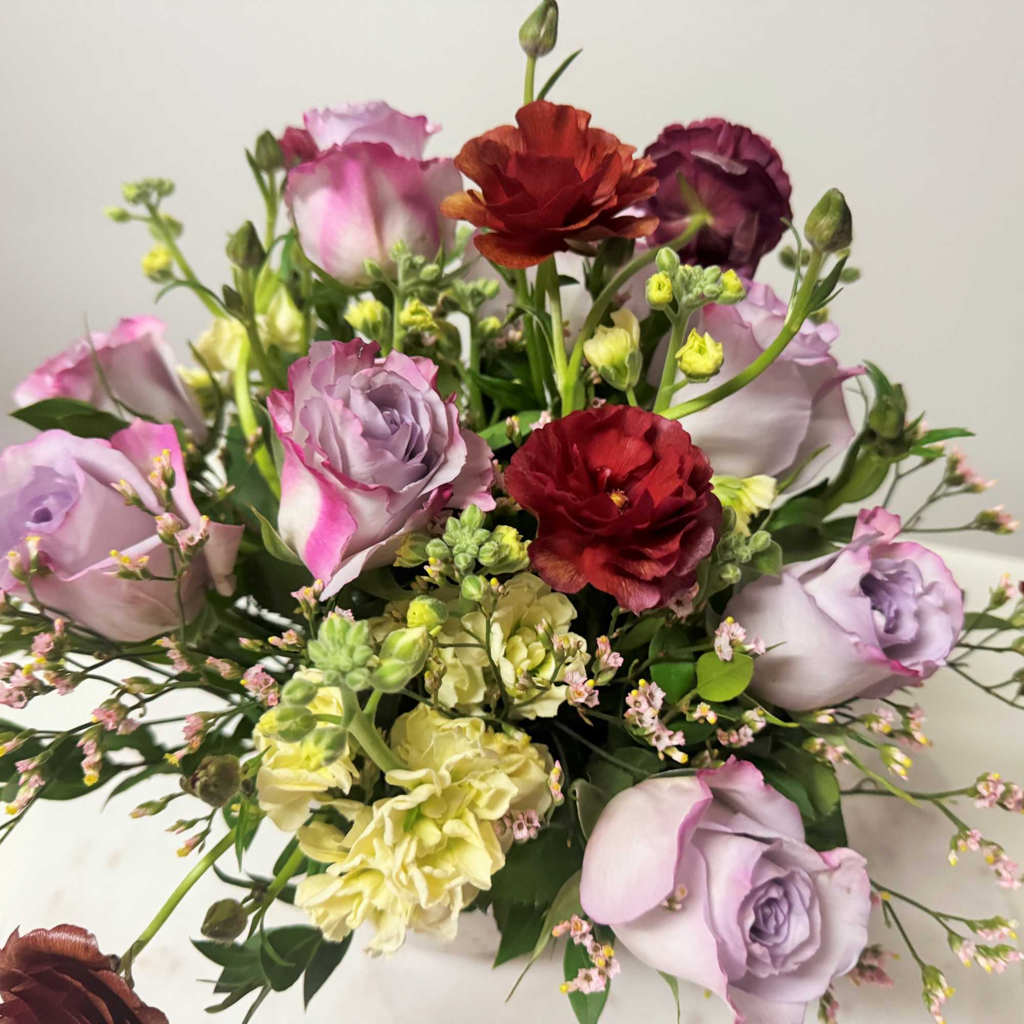 Bouquet of lavender, pink, and red roses with pale yellow flowers
