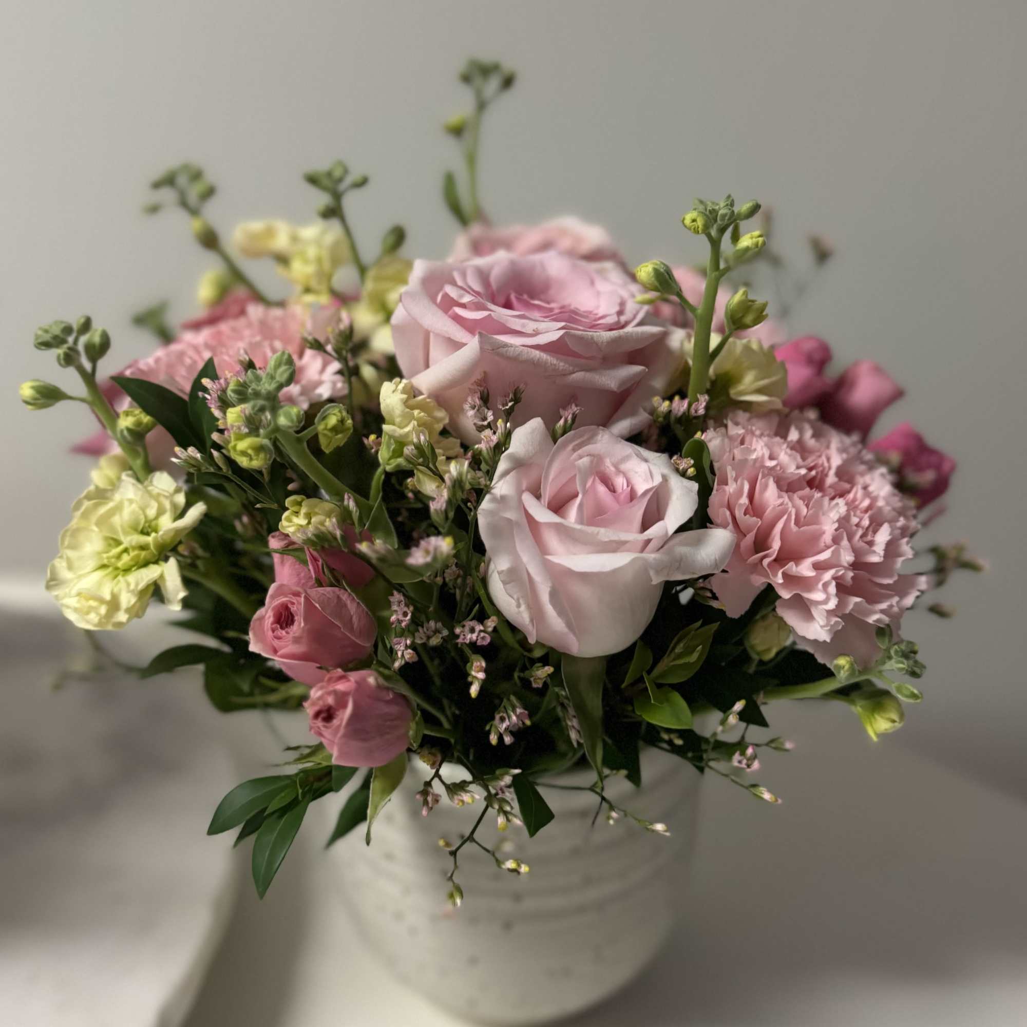 Pink roses and carnations in a white vase