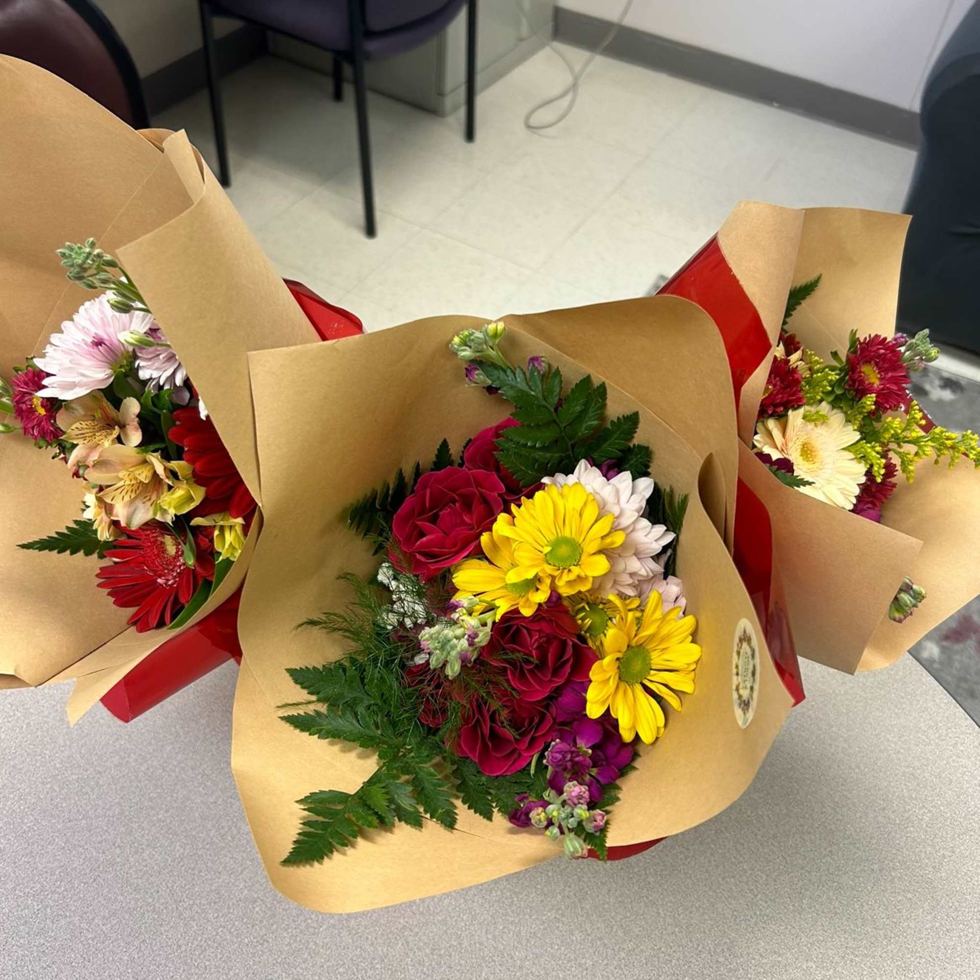 Three wrapped bouquets with mixed flowers in kraft paper