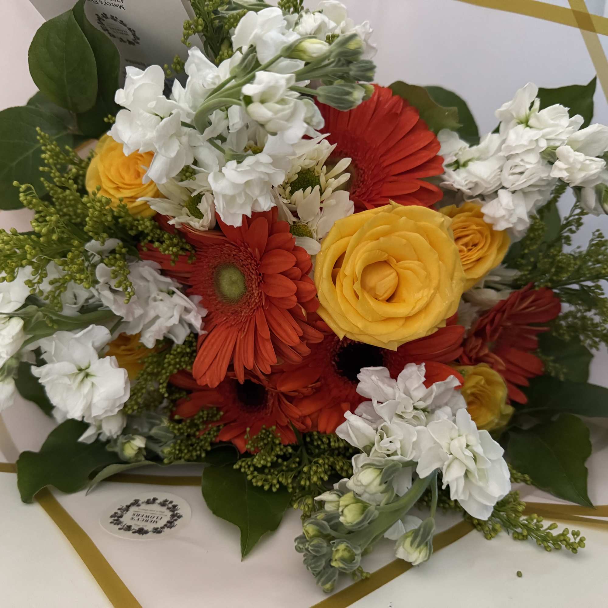Mixed bouquet of yellow, red, and white flowers with greenery