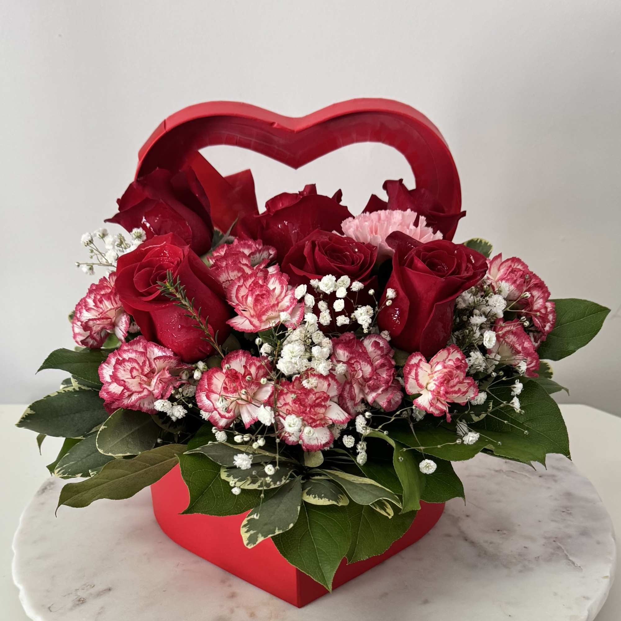 Red roses and pink carnations in a heart-shaped box