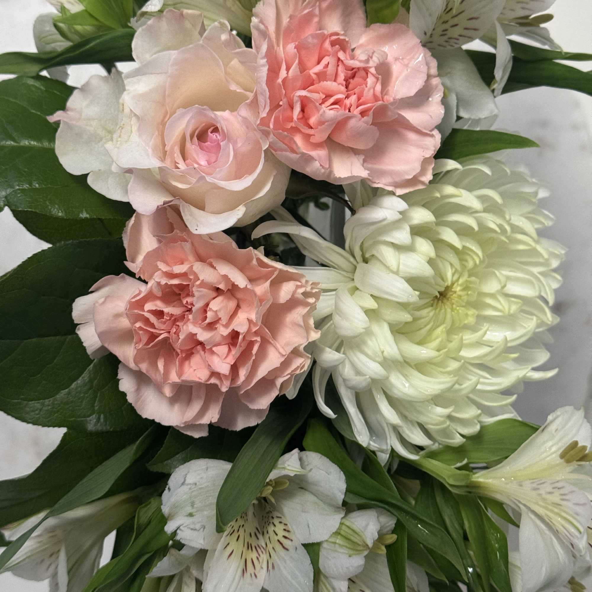 Pink carnations and white lilies with green foliage in a bouquet