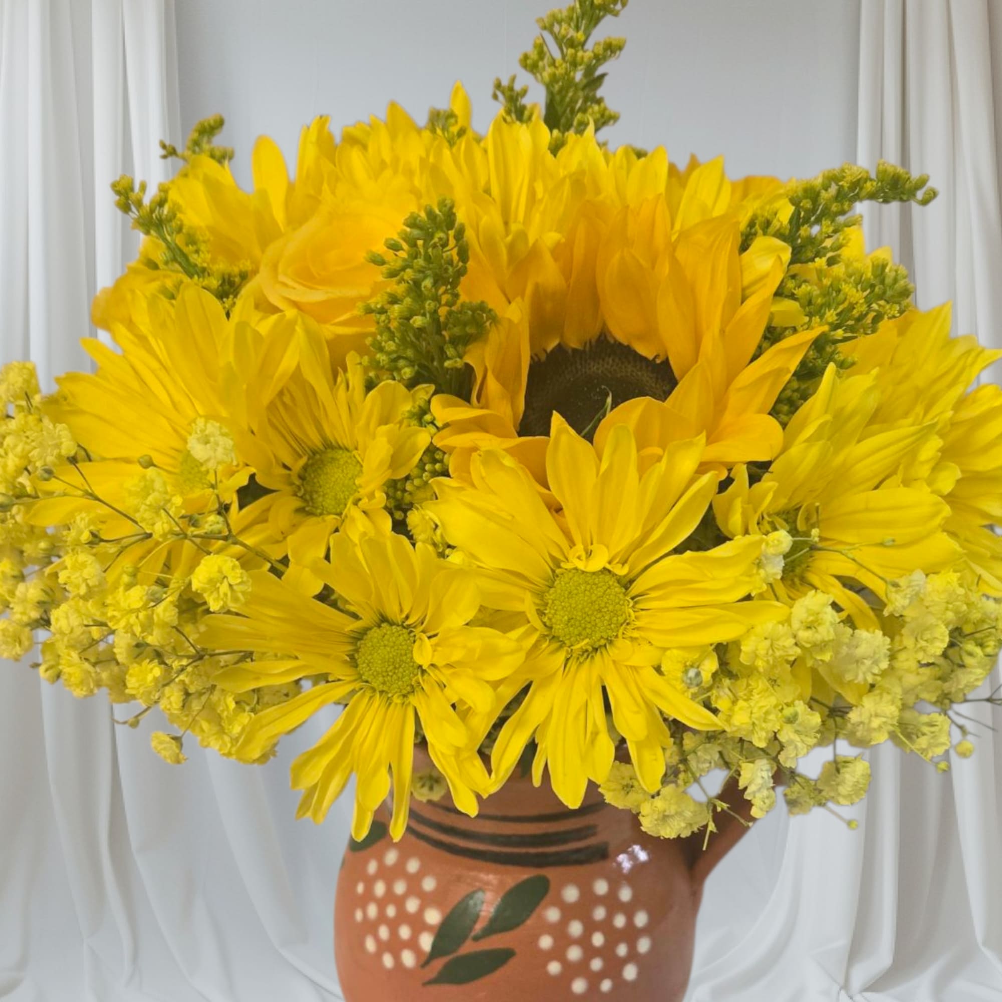 Yellow daisy-like flowers arranged in a painted clay vase