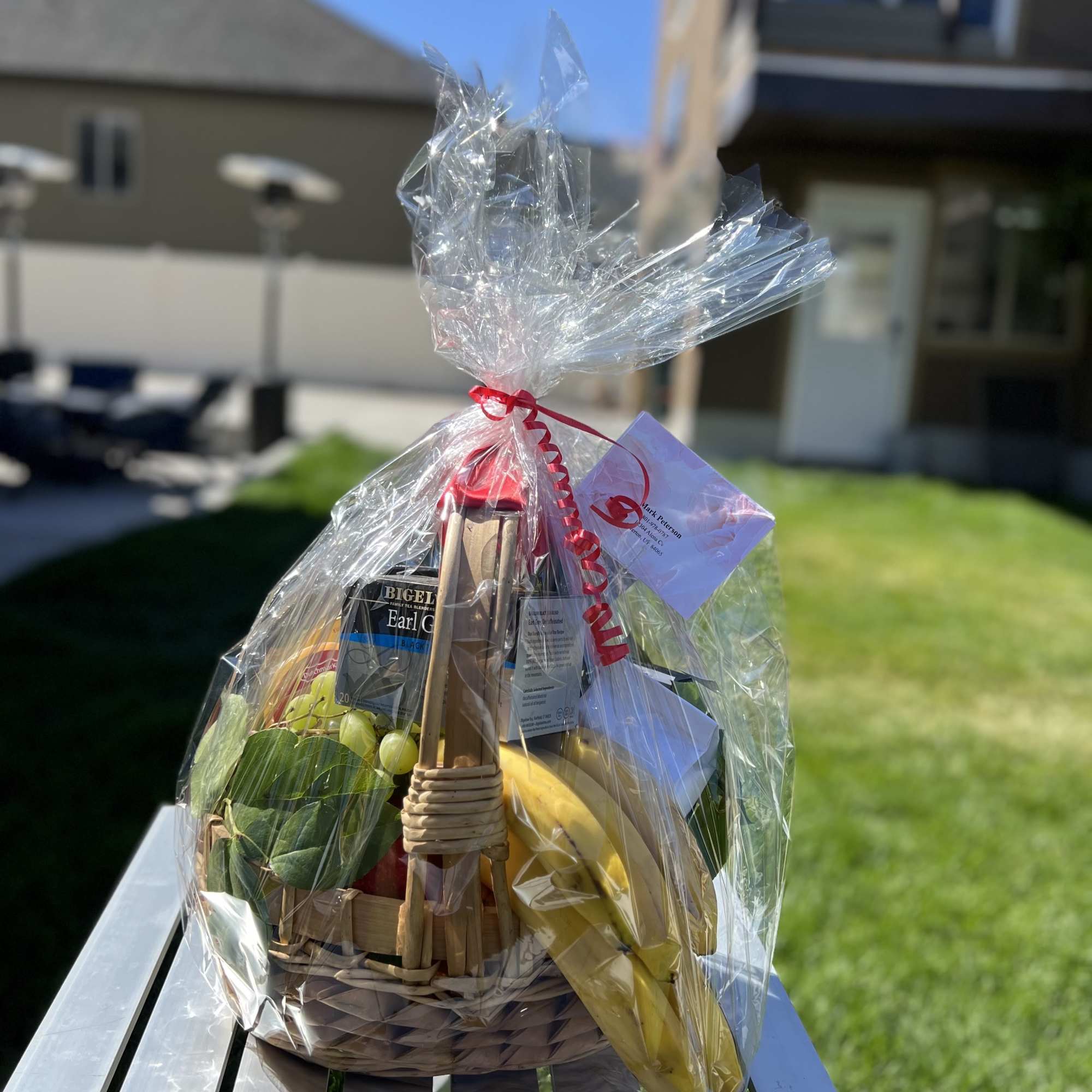 Gift basket wrapped in clear cellophane with fruit and tea