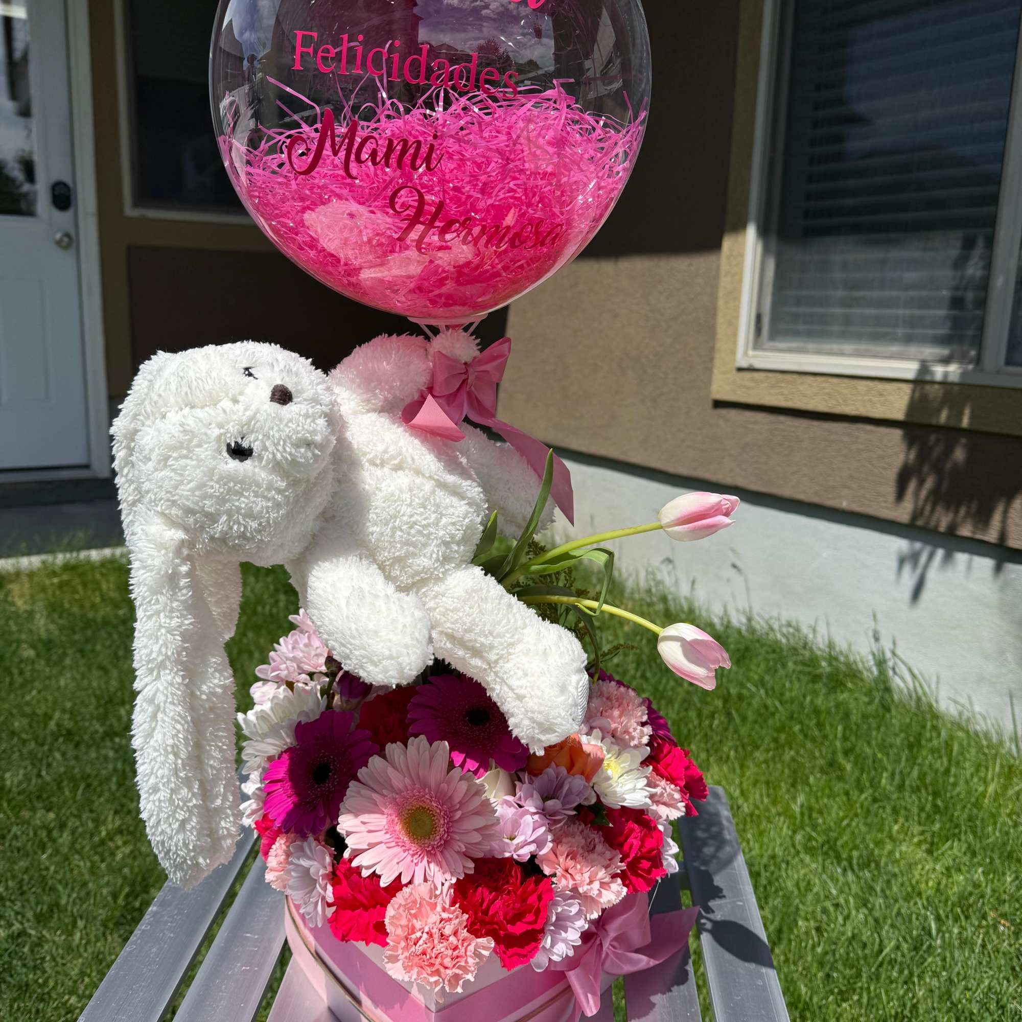Pink flower arrangement with a teddy bear and clear balloon
