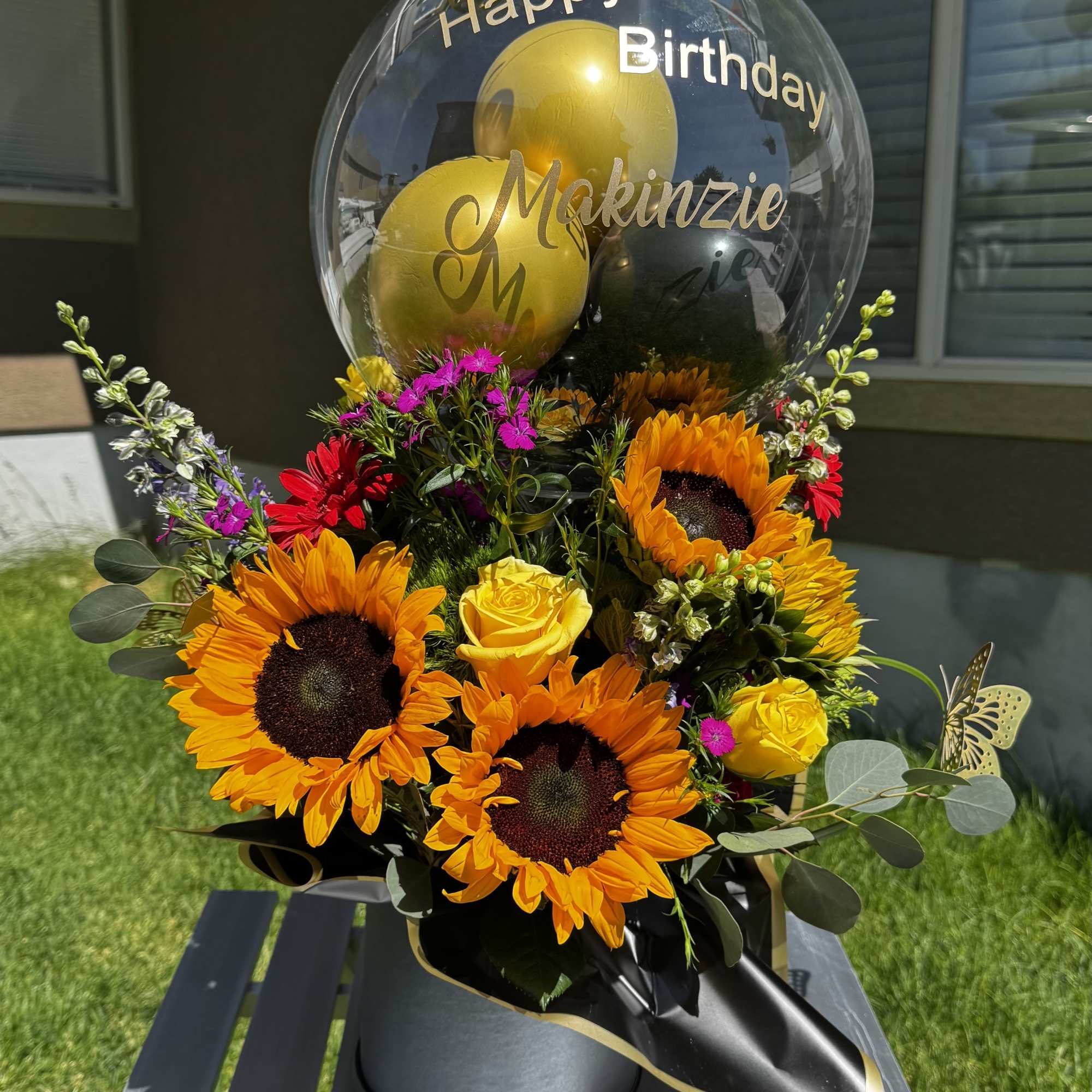 Birthday balloon bouquet with sunflowers and roses in a black container