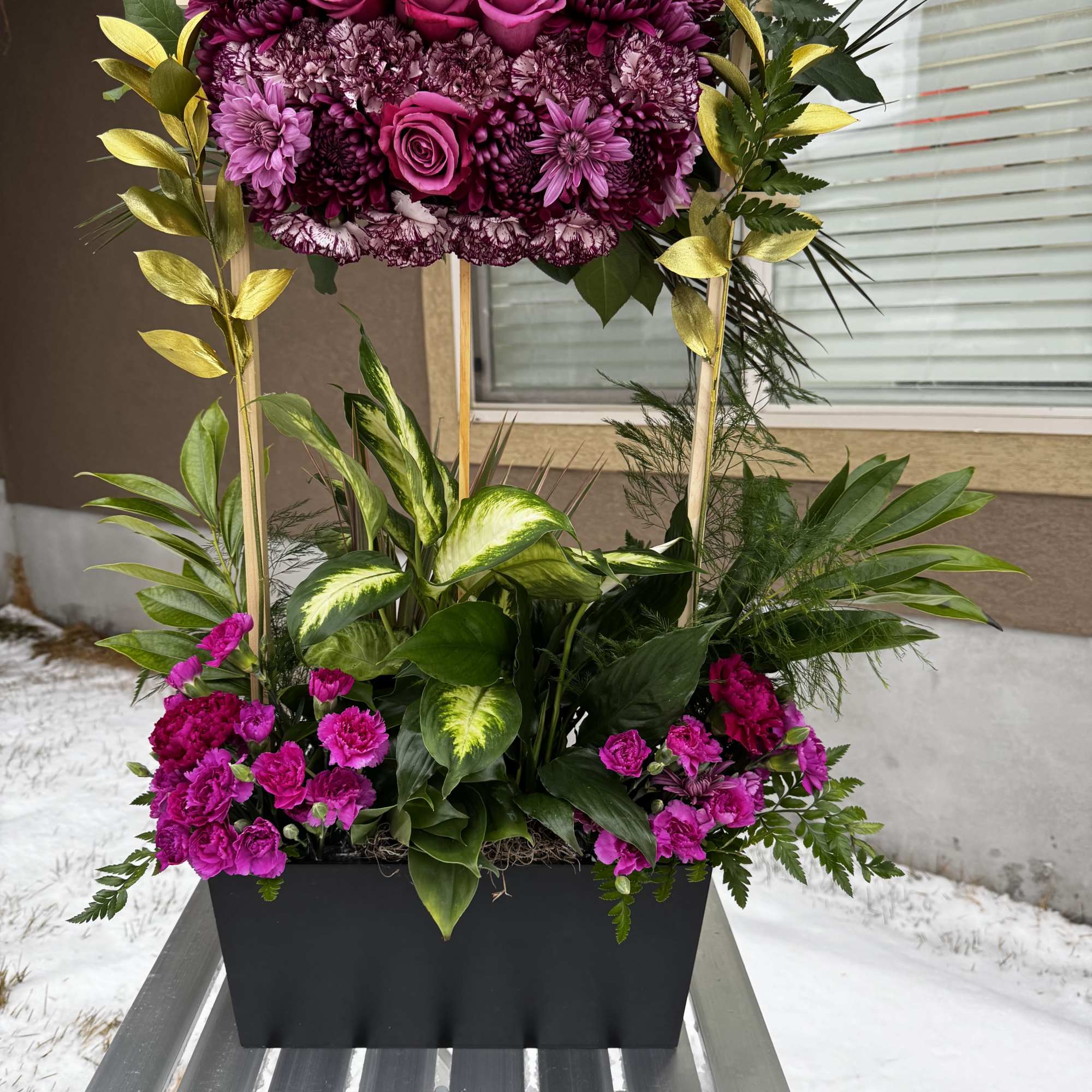 Tall magenta floral arrangement in a black planter with gold accents