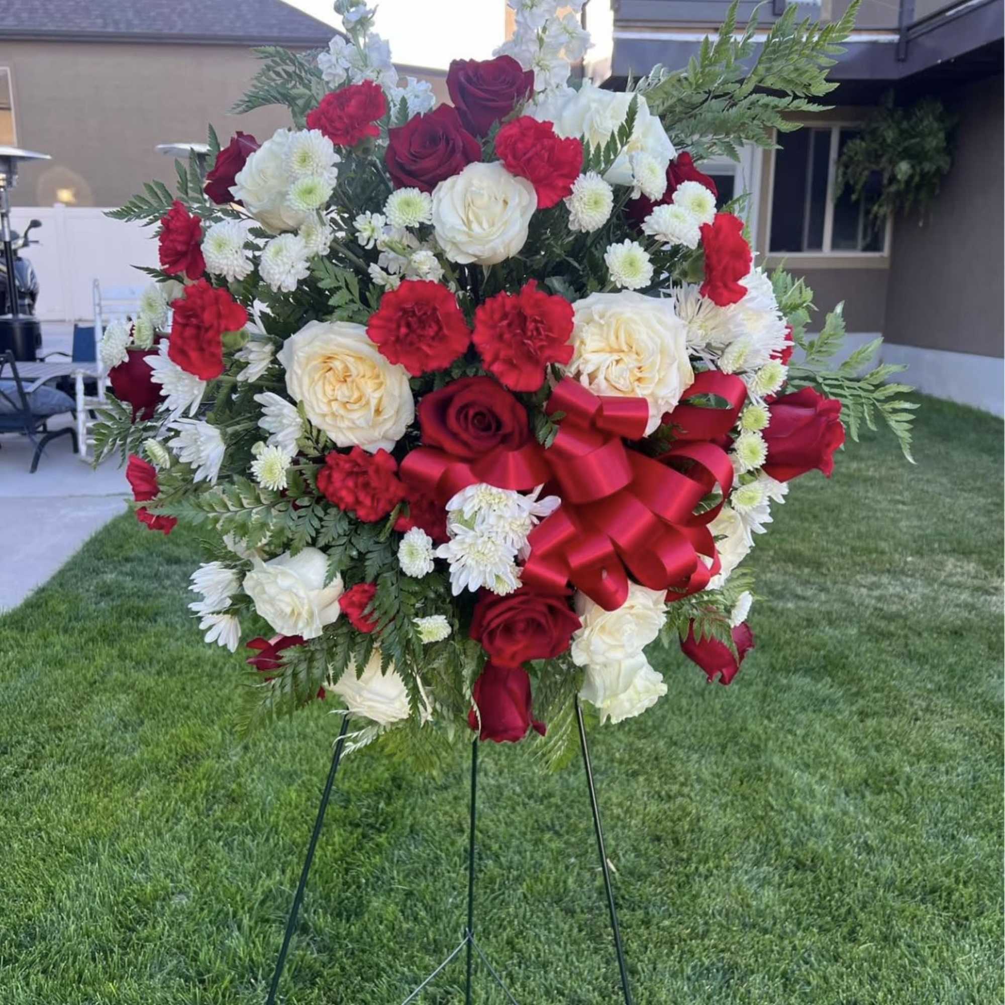 Large red and white rose wreath on a stand with a red bow