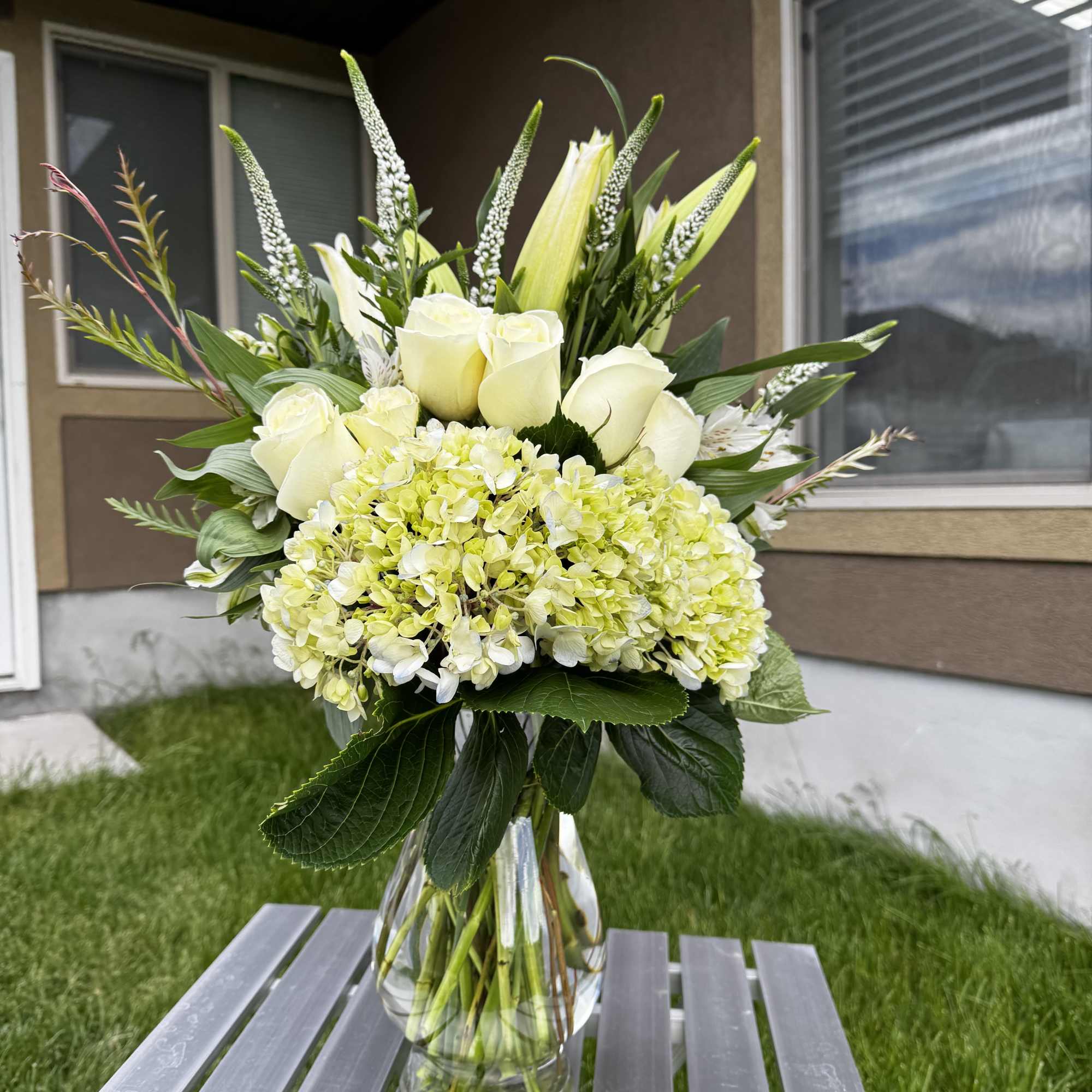 White roses and pale green hydrangea in a clear glass vase