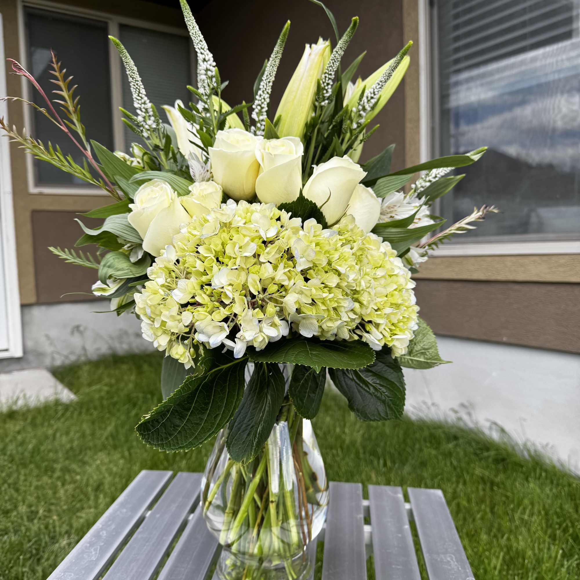 White roses and pale green hydrangeas in a clear glass vase