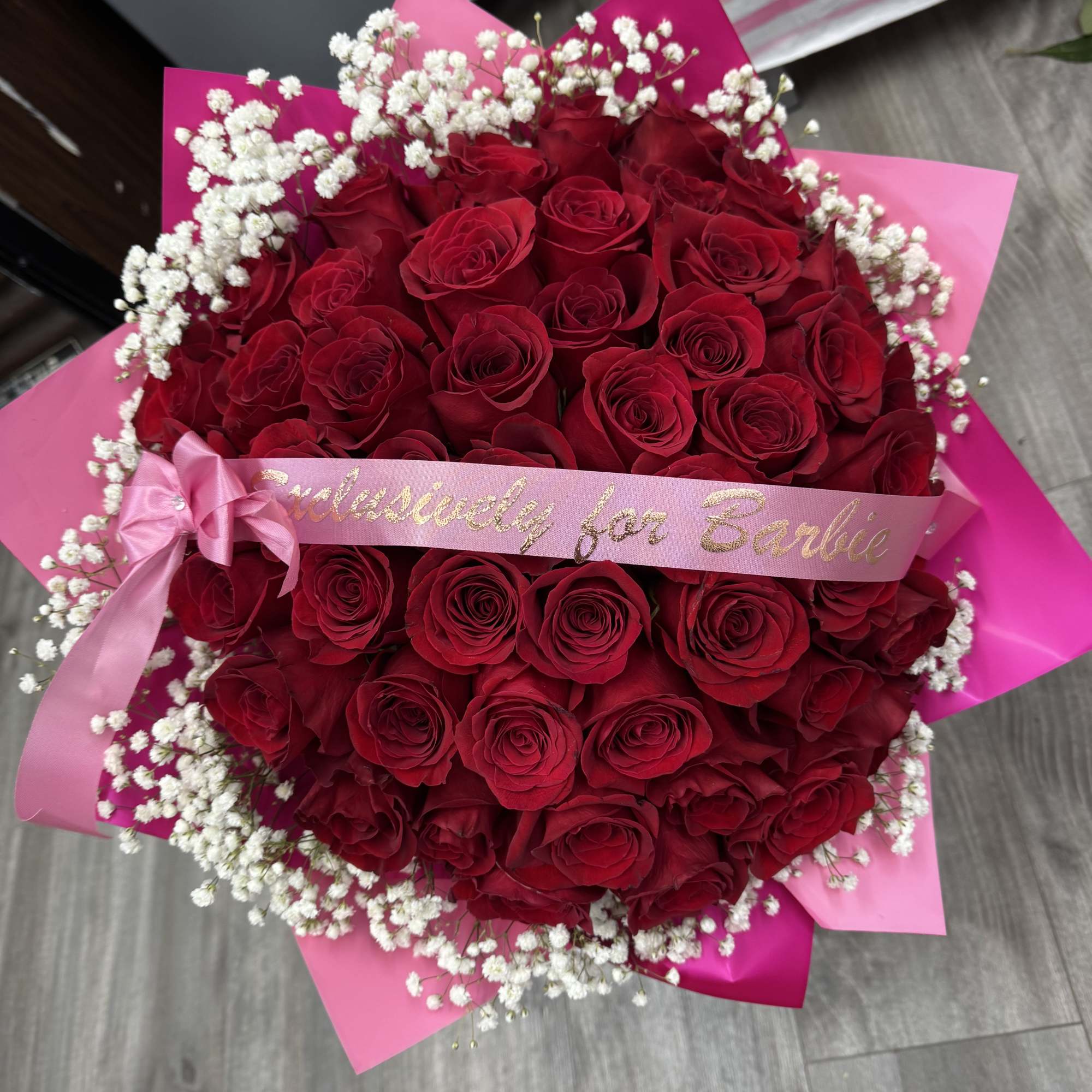 Large bouquet of red roses with white baby's breath and pink ribbon