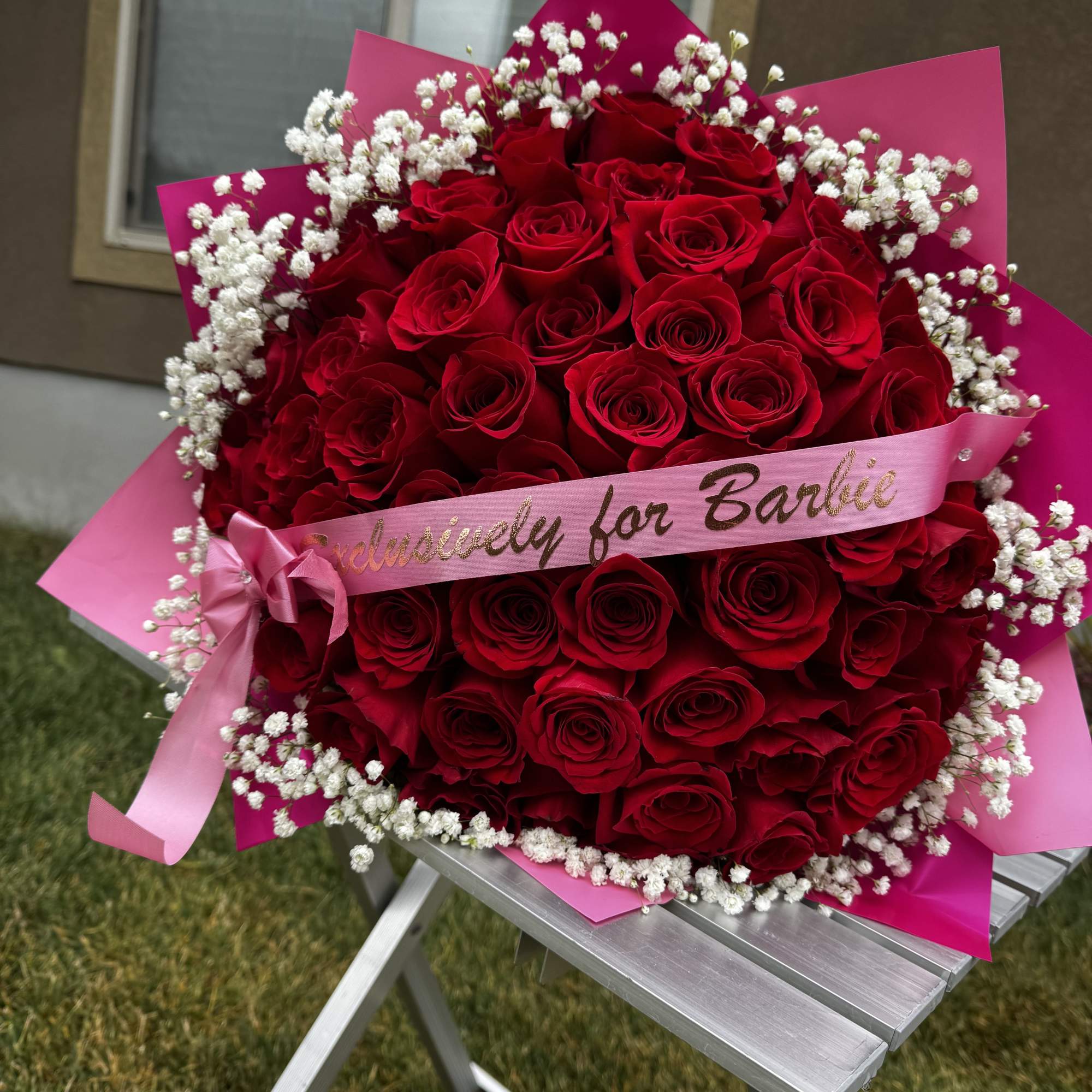 Large bouquet of red roses with white baby's breath and pink wrapping