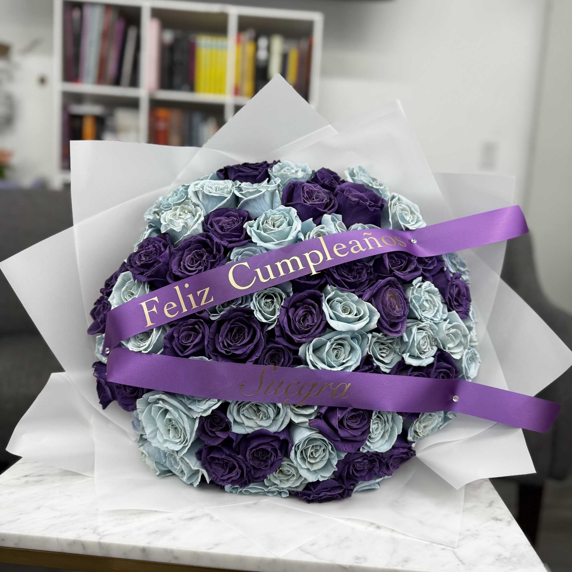 Round bouquet of purple and light blue roses with a birthday ribbon