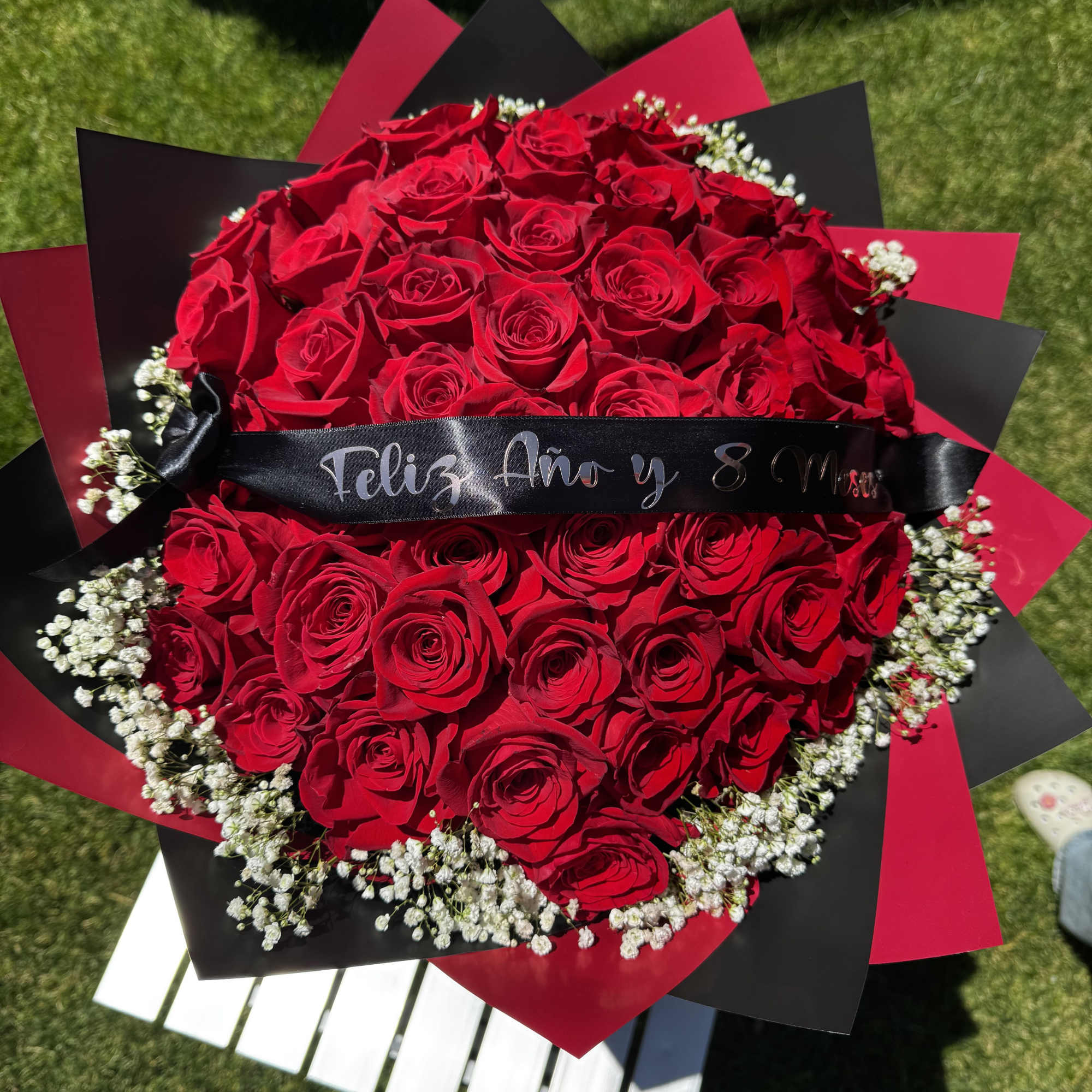Large bouquet of red roses with white baby's breath and black-and-red wrapping