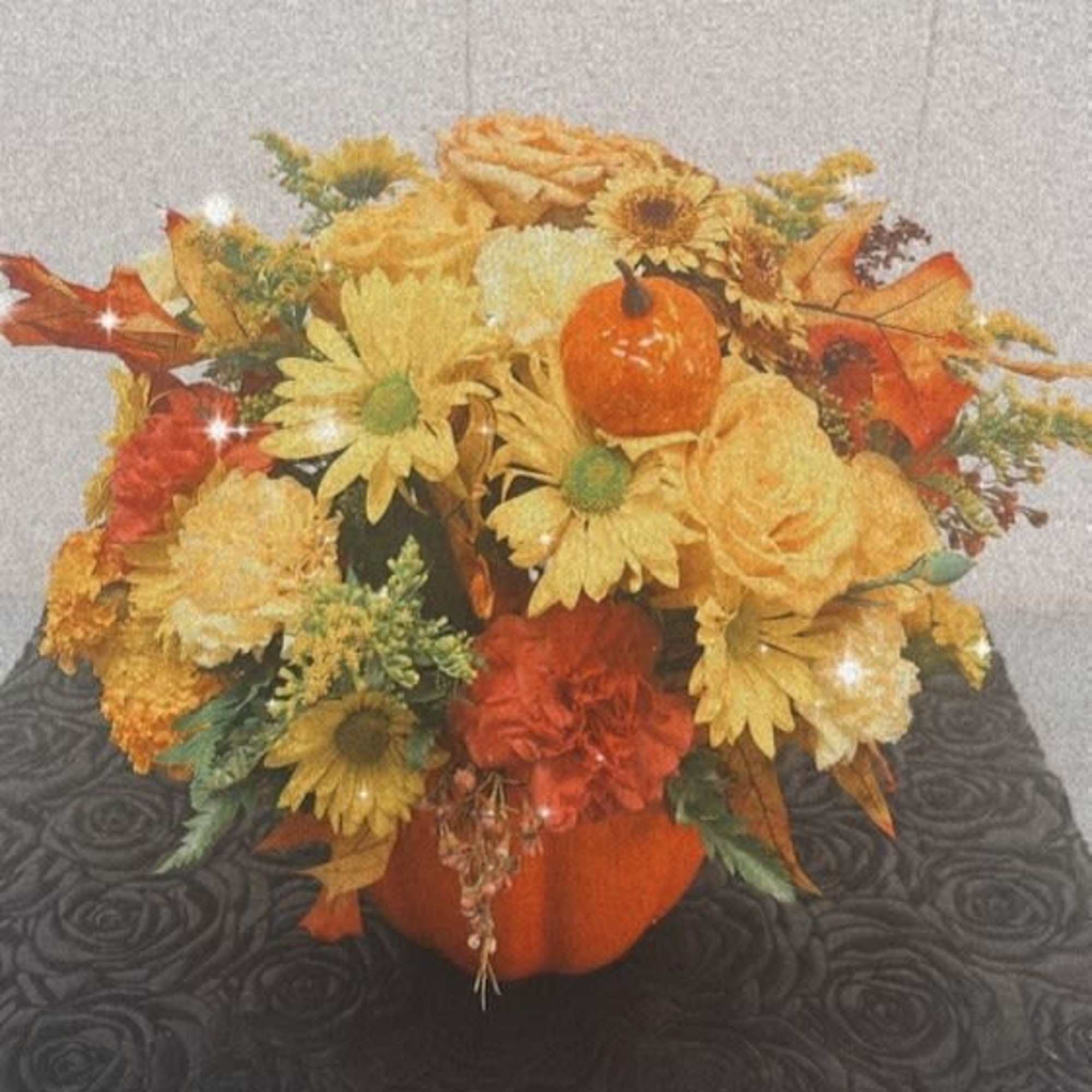 Autumn floral arrangement in a pumpkin-shaped container with yellow and orange blooms