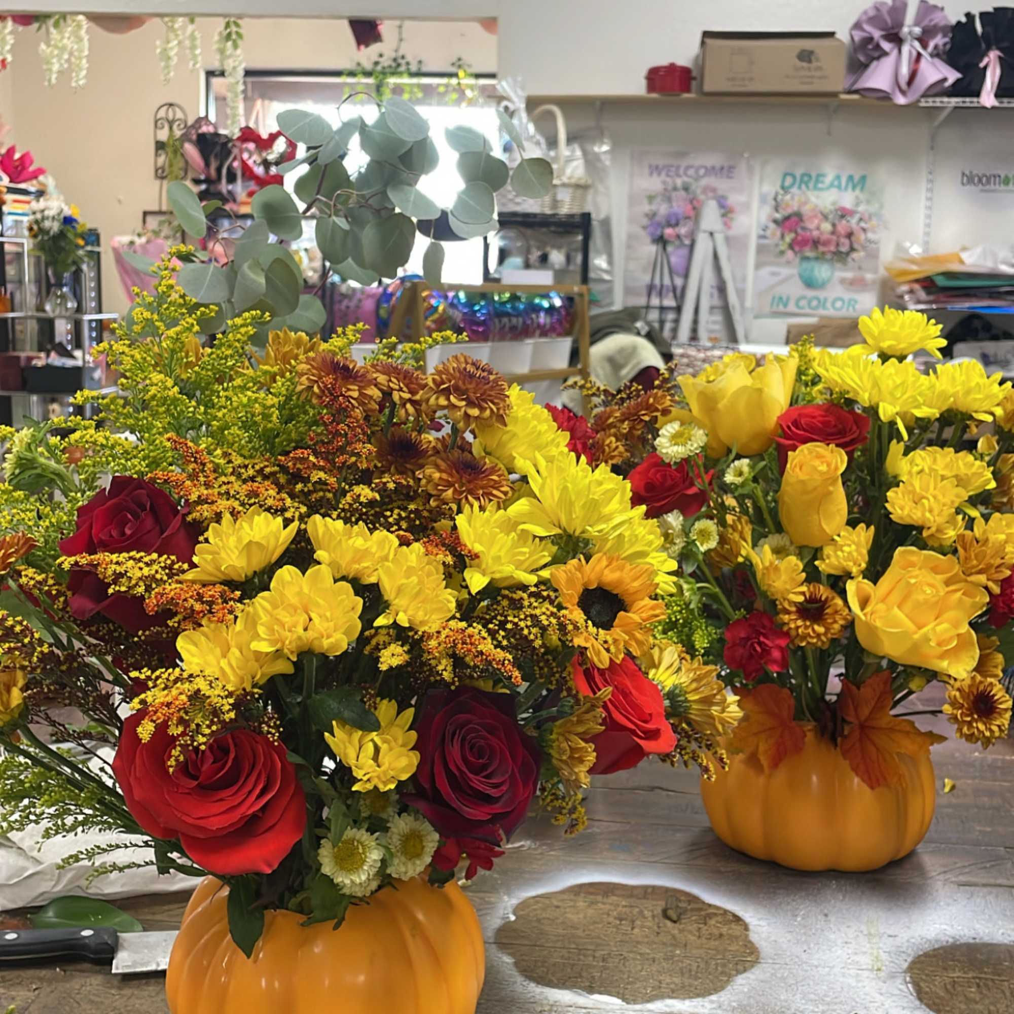 Pumpkin-shaped containers filled with red and yellow flowers