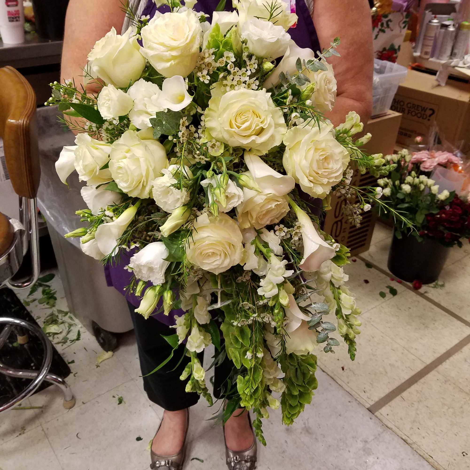 This bouquet is designed with white Mondial roses, calla lilies, lisianthus, snapdragons
