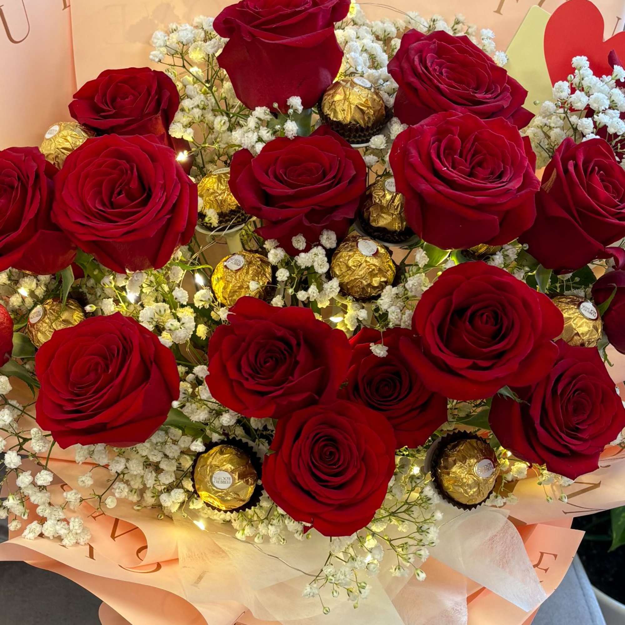 Bouquet of red roses with white baby's breath and gold-wrapped chocolates