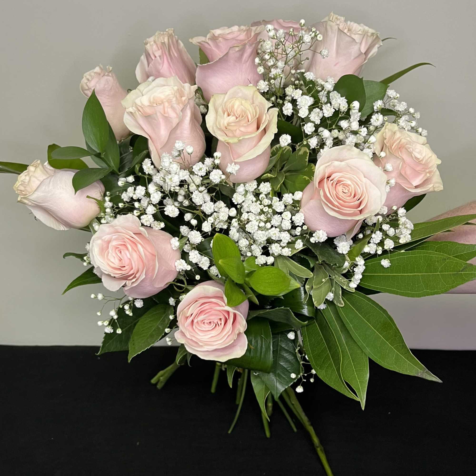 Wrapped bouquet of light pink roses with babies breath, ready to go